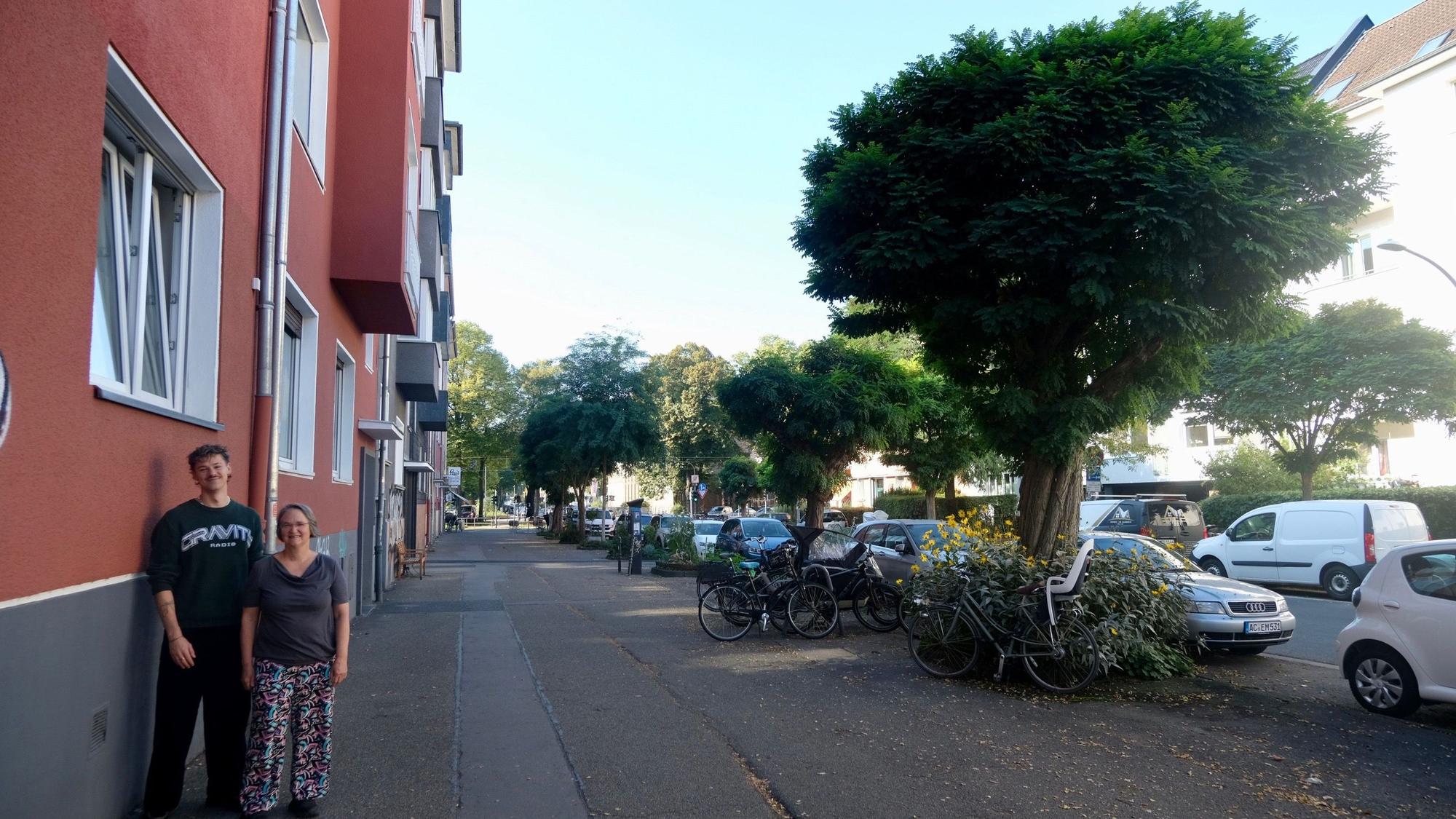 Ein Mann und eine Frau stehen vor einem Fallrohr an einer Hausfassade.