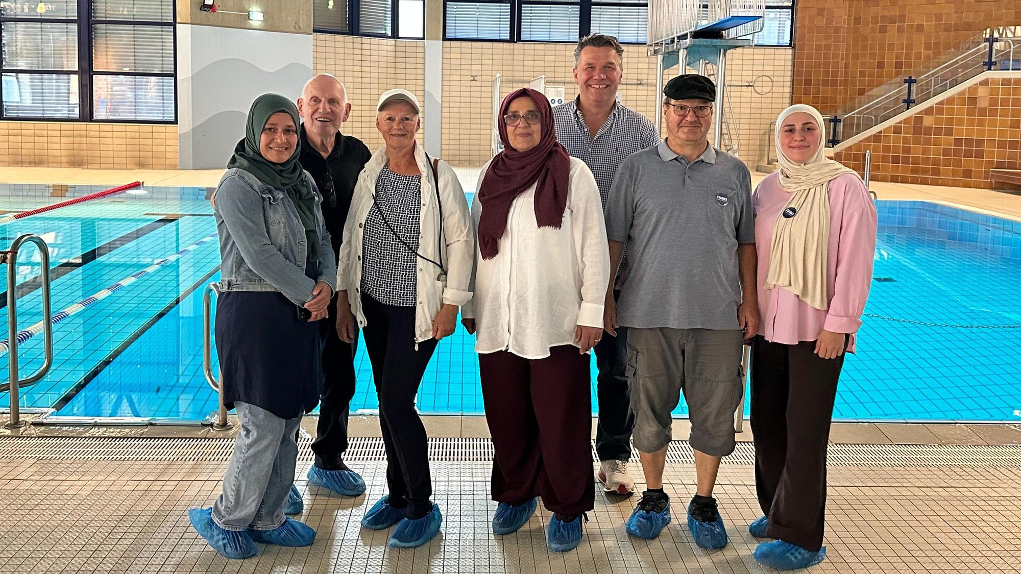 Aktivistinnen für und Unterstützer:innen des Frauenschwimmens stehen am Rand eines Schwimmbeckens.