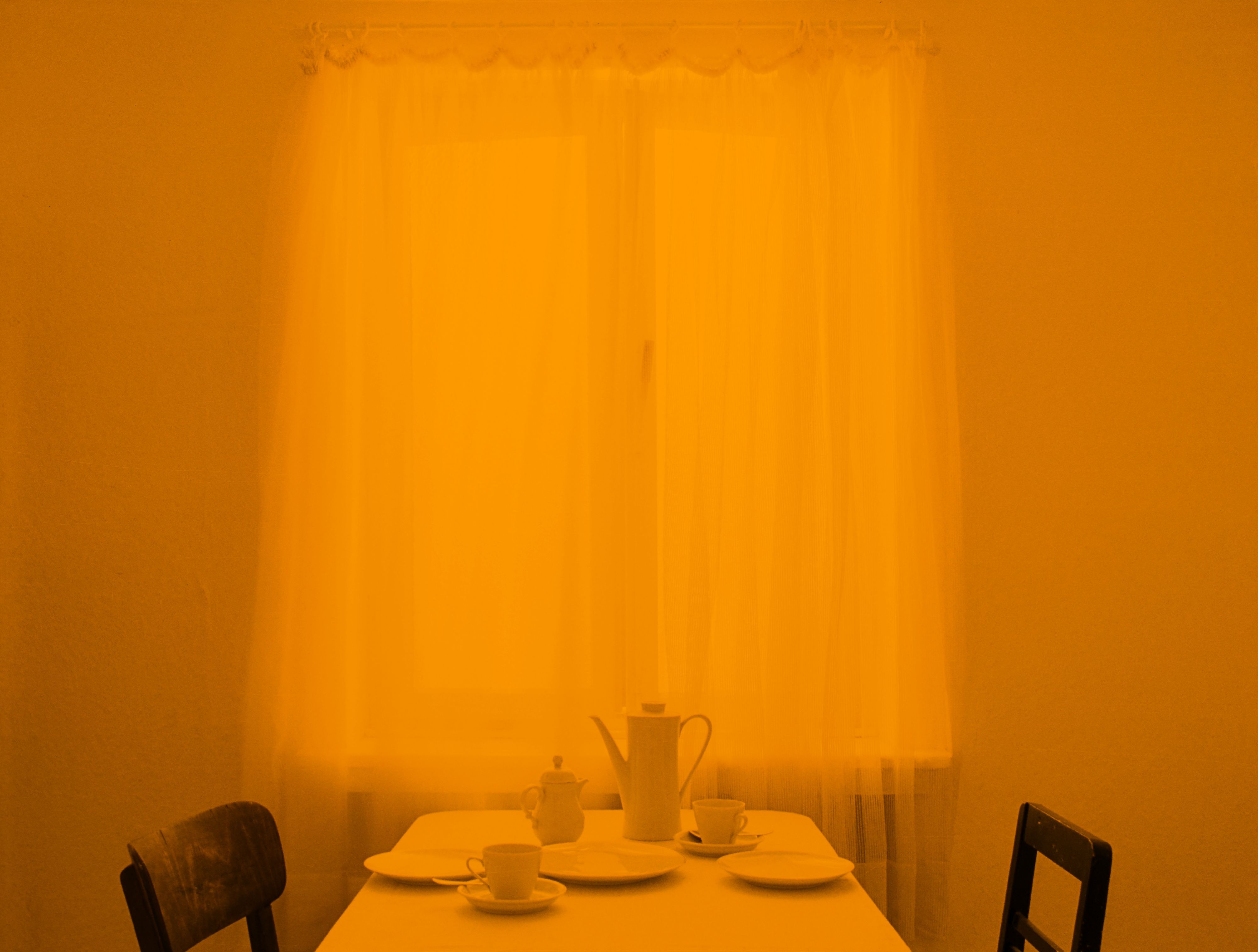 Das Foto zeigt ein Esszimmer in orangenem Licht.