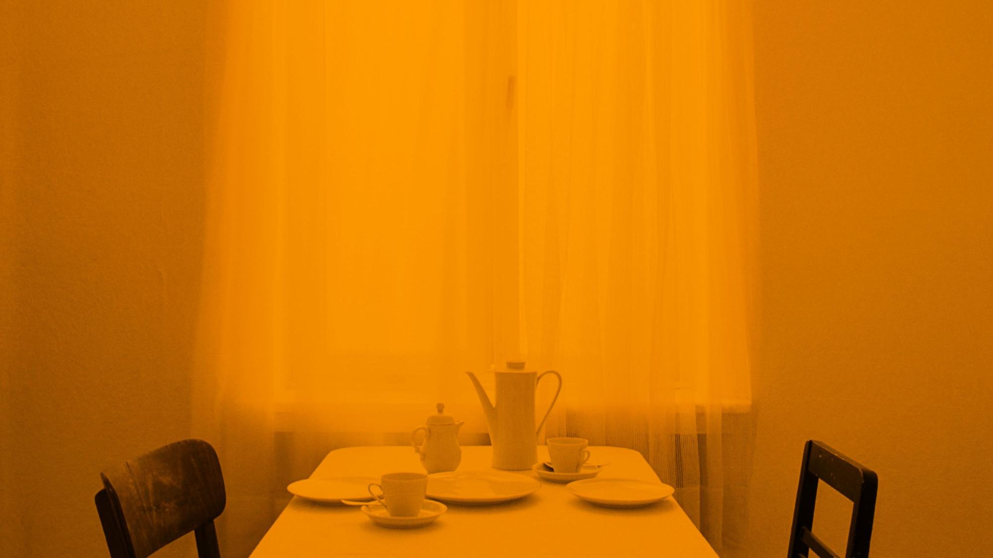 Das Foto zeigt ein Esszimmer in orangenem Licht.
