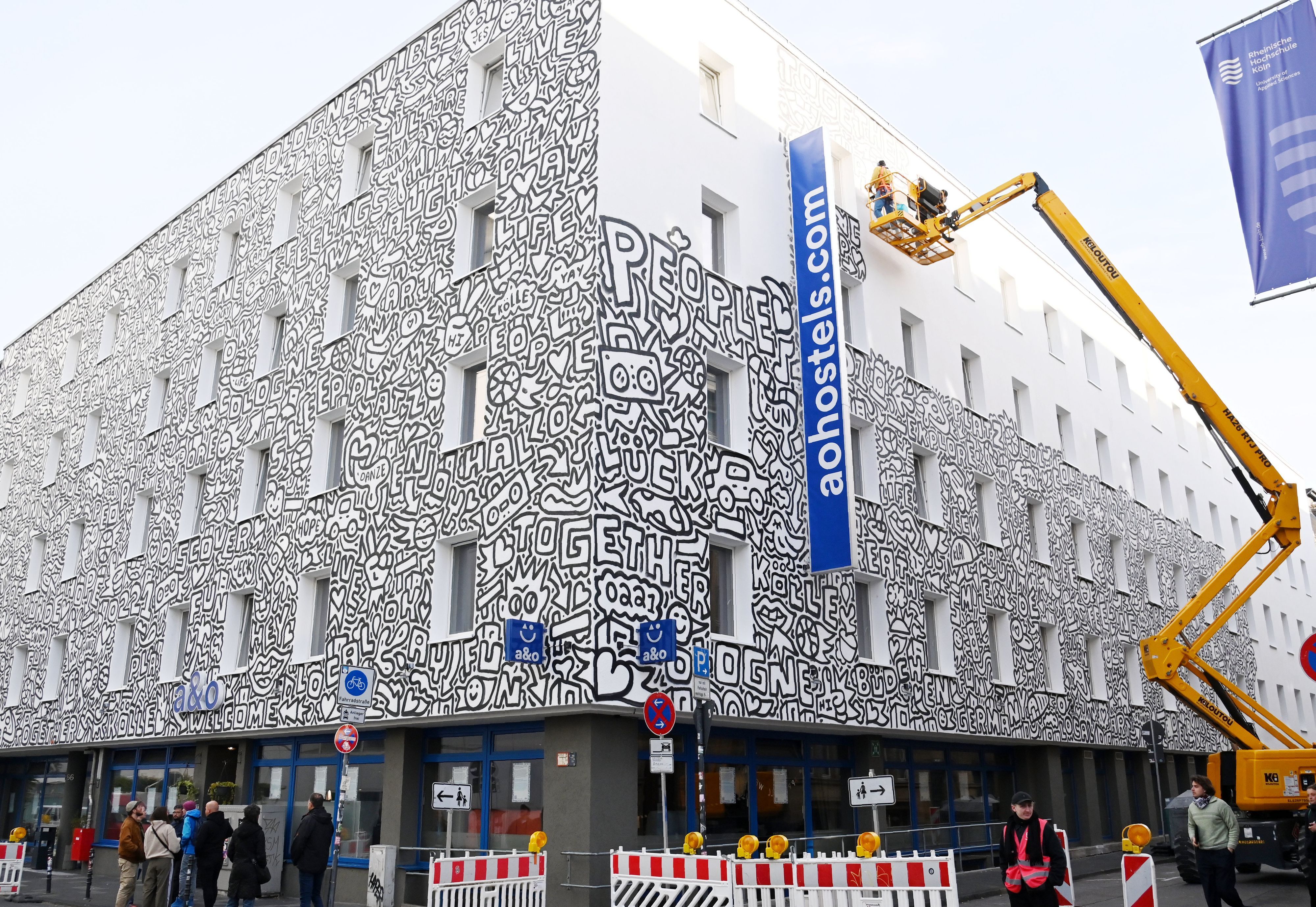 22.10.2026 Köln. Der New Yorker Künstler Timothy Goodman gestaltet mit seinem Werk „People Love People“ die Fassade des a&o Hostels Köln Neumarkt. Foto: Alexander Schwaiger