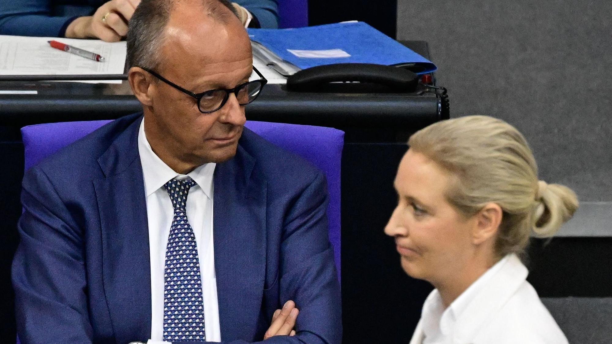 Bundeskanzler Friedrich Merz (CDU) im Bundestag. Im Vordergrund geht AfD-Chefin Alice Weidel entlang. (Archivbild)