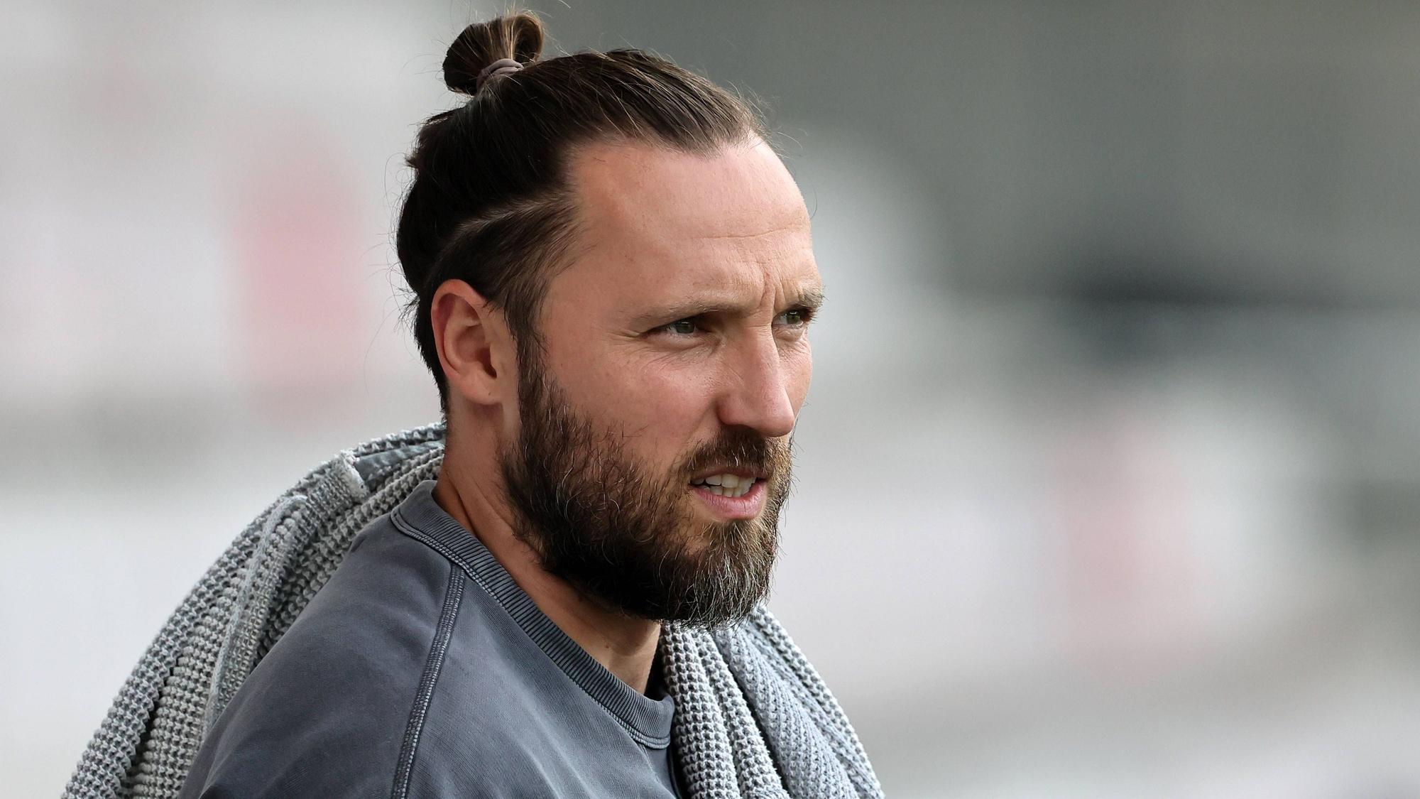 Marco Höger steht in Zivil am Spielfeldrand.