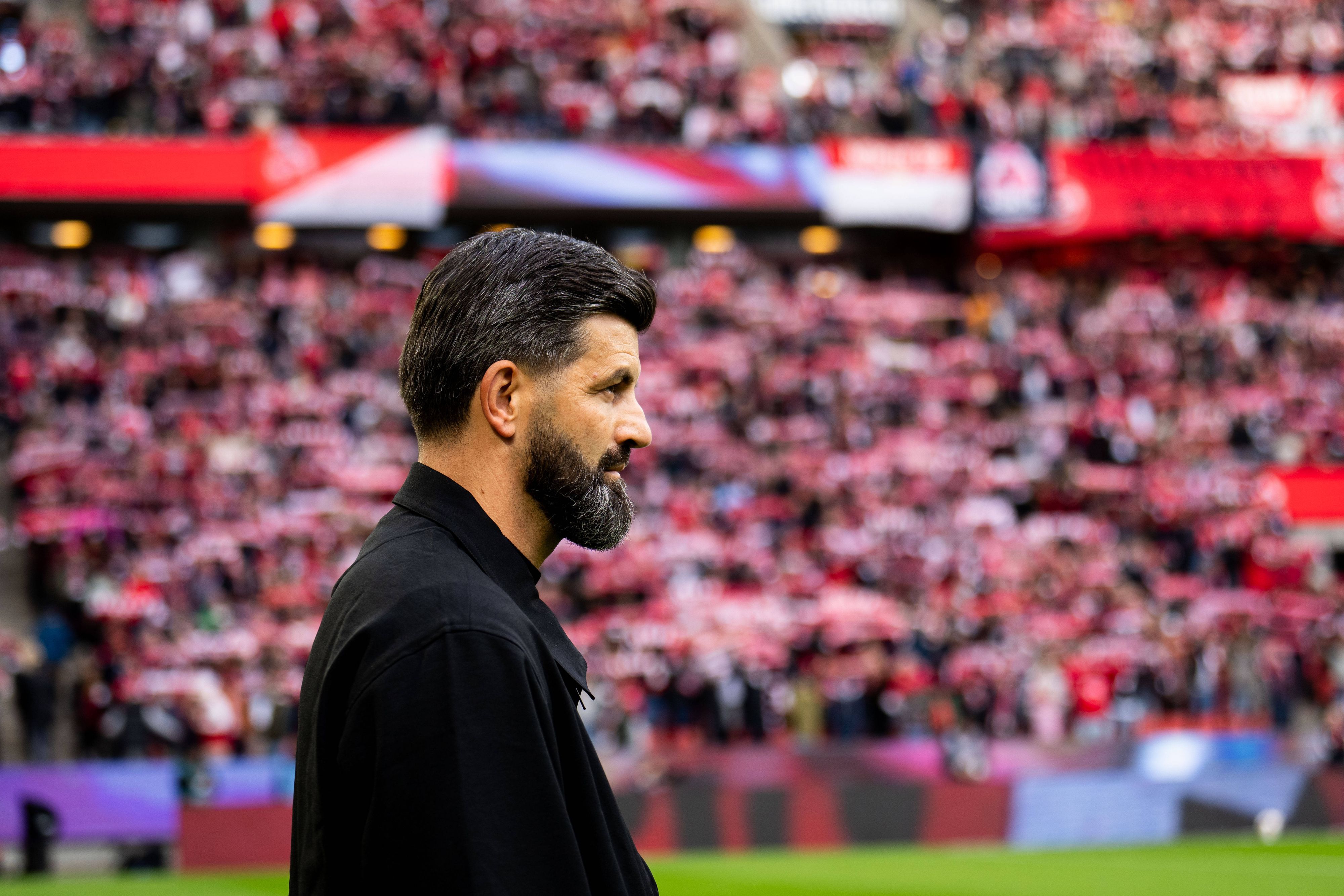 Miron Muslic steht im Stadion, im Hintergrund sind FC-Fans zu sehen.