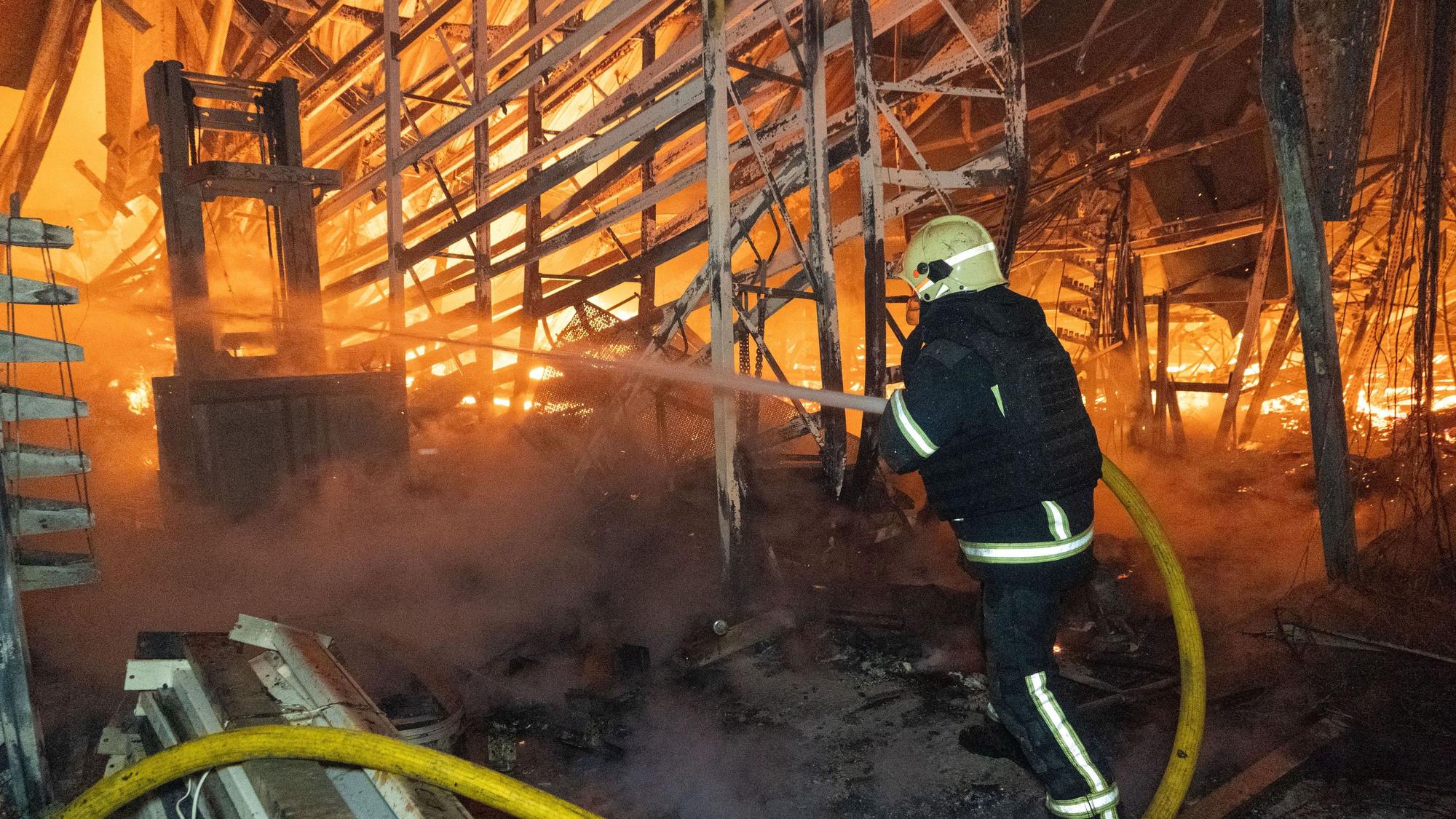 Ein Feuerwehrmann versucht, nach einem russischen Luftangriff am 25. Oktober einen Brand in einem Einkaufszentrum in Charkiw zu löschen.