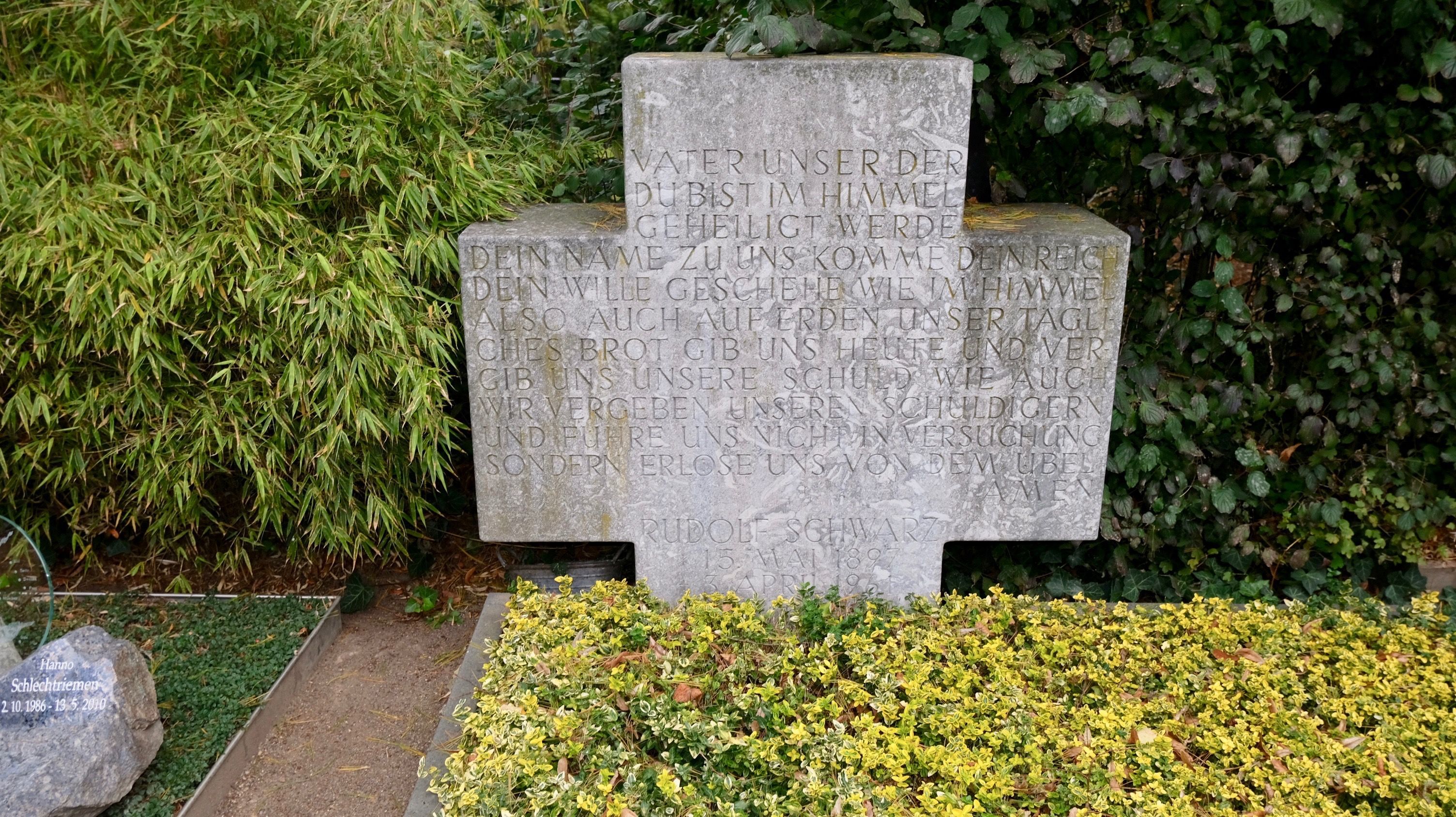 Ein breites Kreuz aus Stein steht auf einer Grabstätte.