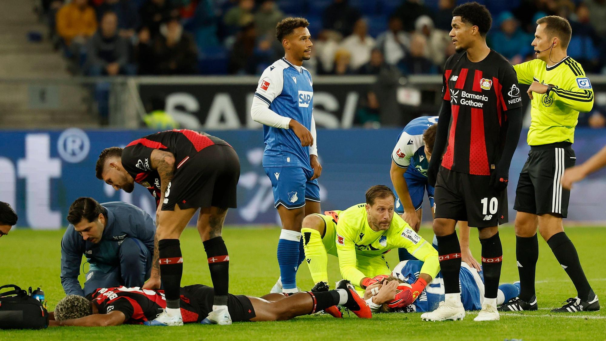 v.l.n.r.: LoÃc Badà , Loic Bade Bayer 04 Leverkusen und Max Moerstedt TSG Hoffenheim knallen mit den Köpfen zusammen und bleiben liegen, im Bundesliga-Spiel zwischen der TSG 1899 Hoffenheim und Bayer 04 Leverkusen in der PreZero Arena, Sinsheim, Deutschland, am 25. Oktober 2026. in action during the Bundesliga match between TSG 1899 Hoffenheim and Bayer 04 Leverkusen at the PreZero Arena, Sinsheim, Germany, on October 25, 2026. DFB/DFL REGULATIONS PROHIBIT ANY USE OF PHOTOGRAPHS AS IMAGE SEQUENCES AND/OR QUASI-VIDEO, *** From left to right: Loïc Bade of Bayer 04 Leverkusen and Max Moerstedt of TSG Hoffenheim collide heads and remain on the ground during the Bundesliga match between TSG 1899 Hoffenheim and Bayer 04 Leverkusen at the PreZero Arena, Sinsheim, Germany, on October 25, 2026, in action during the Bundesliga match between TSG 1899 Hoffenheim and Bayer 04 Leverkusen at the PreZero Arena, Sinsheim, Germany, on October 25, 2026. DFB and DFL regulations prohibit any use of photographs as image sequences and/or quasi-video, Copyright: HMBxMedia/xHeikoxBecker