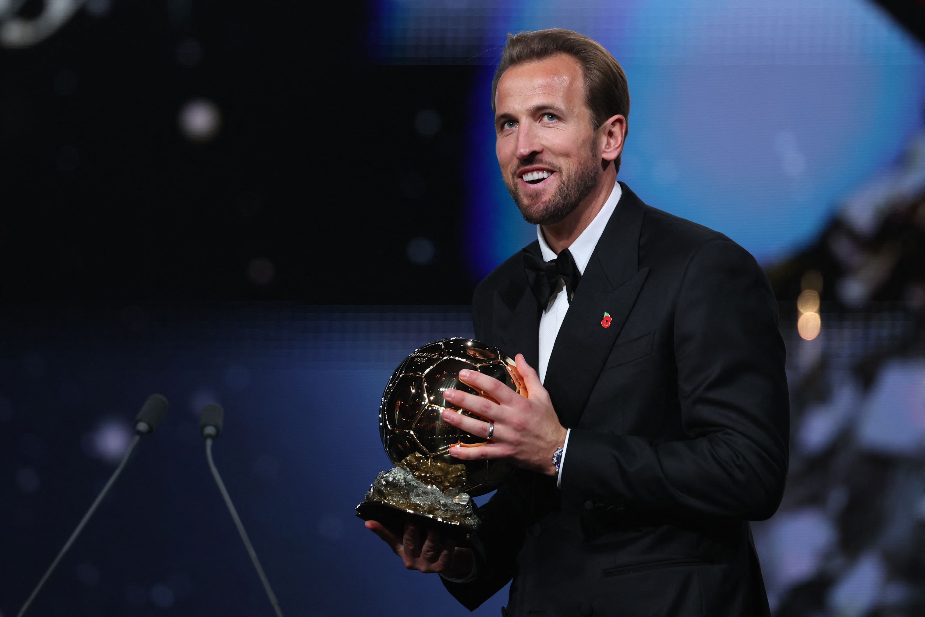Auf der Bühne hält Weltfußballer Harry Kane den Ballon d'Or in den Händen.