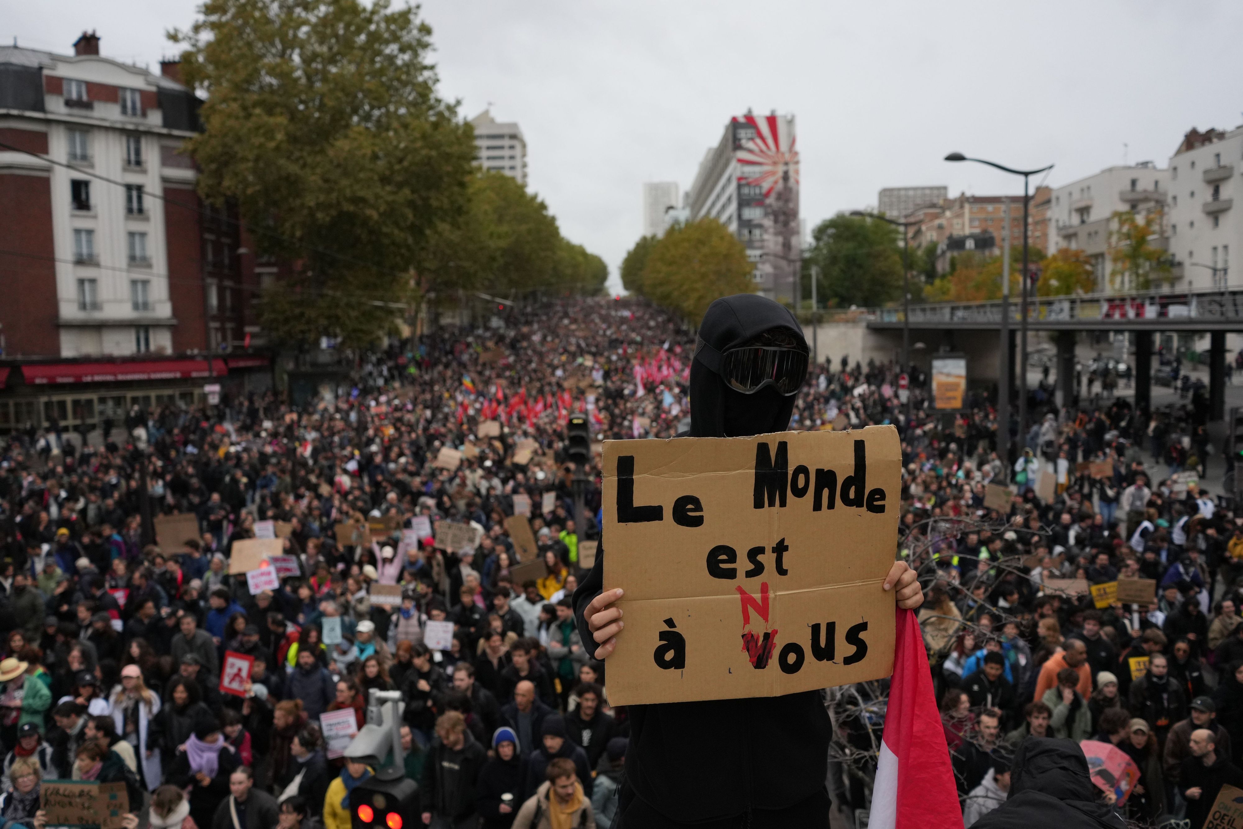 Ein Demonstrant hält in Paris ein Schild mit der Aufschrift „Die Welt gehört uns“ hoch.
