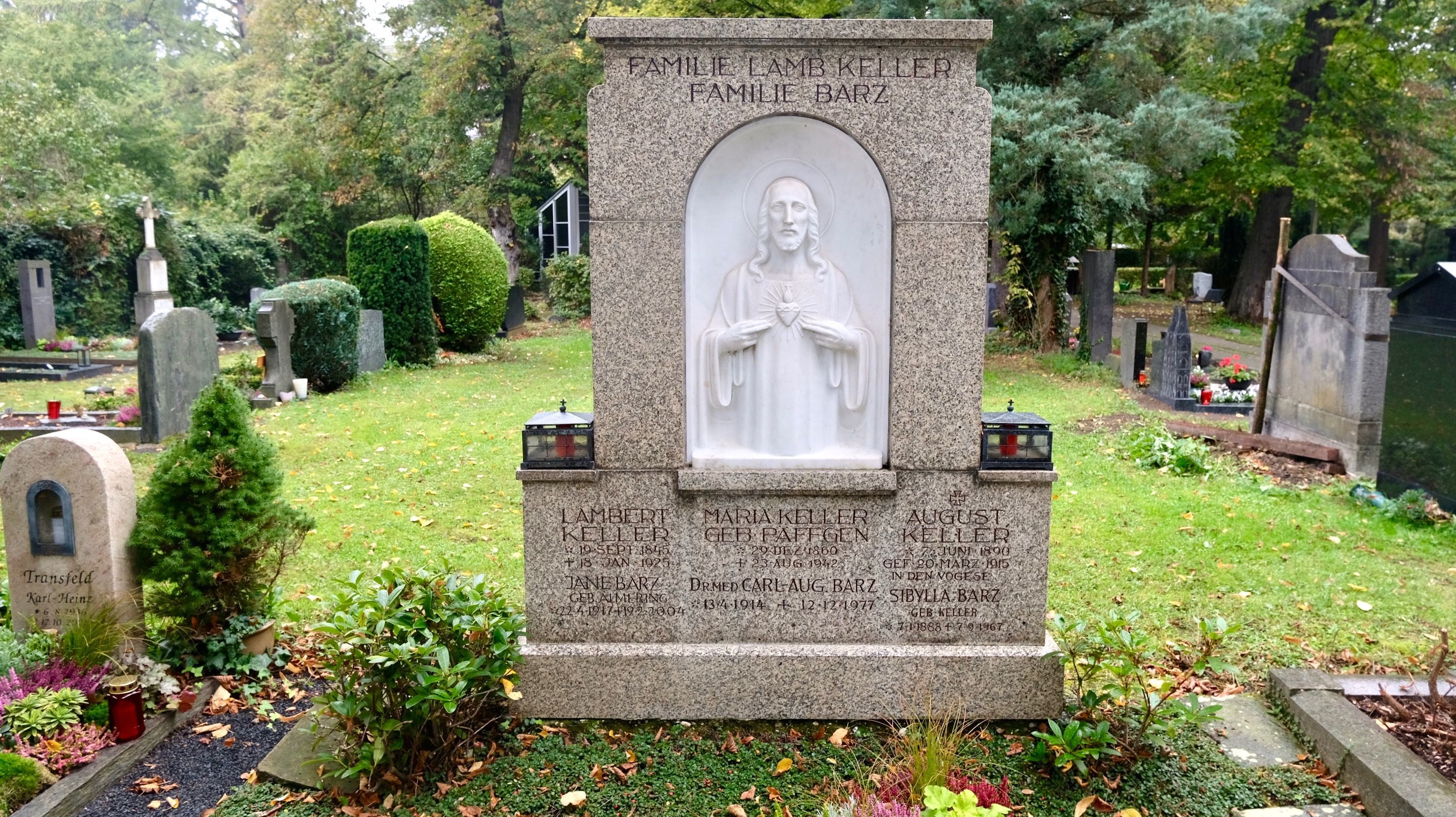 Ein großer Grabstein mit einer eingelassenen Heiligenfigur steht auf einem Friedhof.