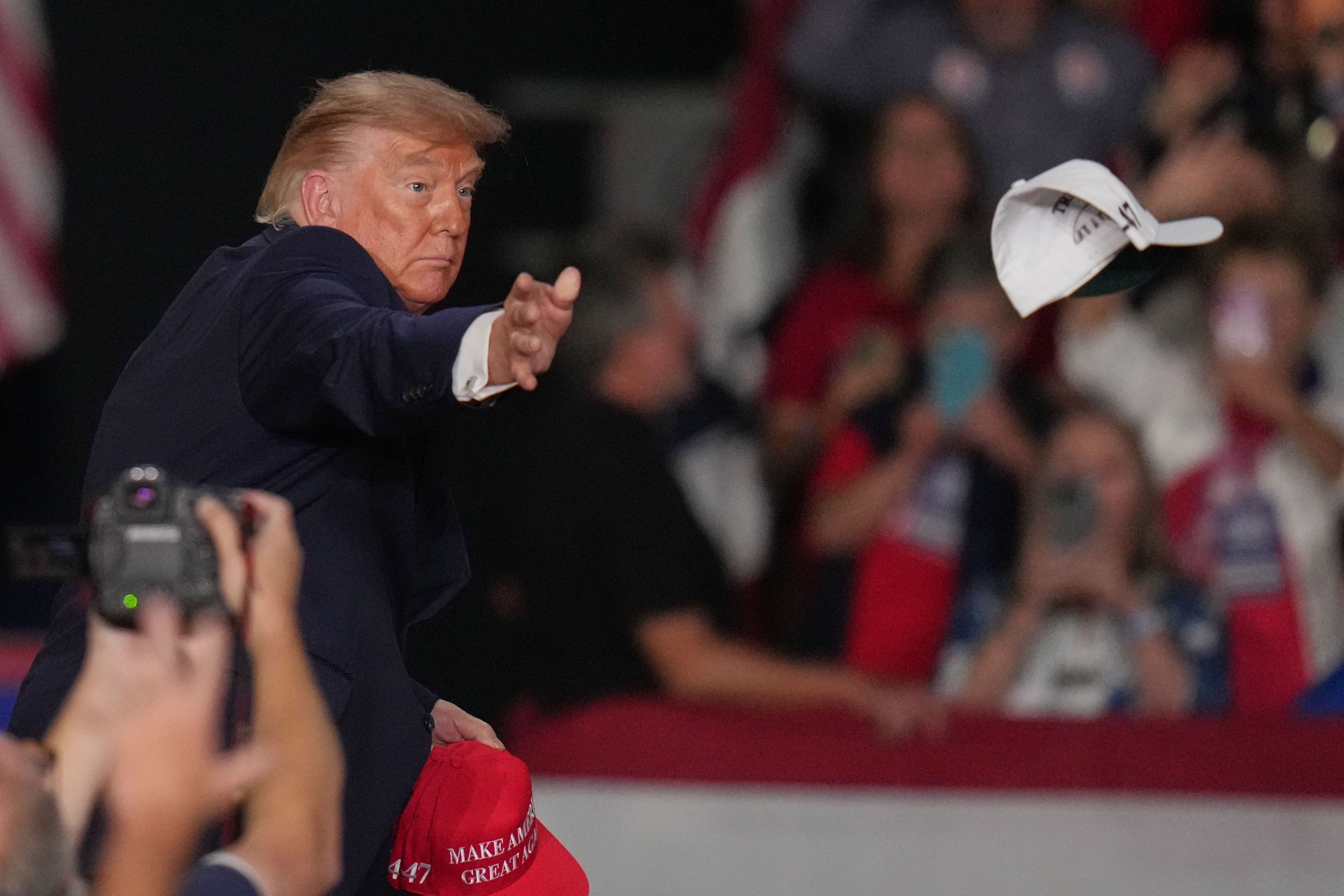 dpatopbilder - 26.10.2026, USA, Korinth: US-Präsident Donald Trump wirft bei einer Wahlkampfveranstaltung in der Crossroads Arena Kappen in die Menge. Foto: Jeff Roberson/AP/dpa +++ dpa-Bildfunk +++