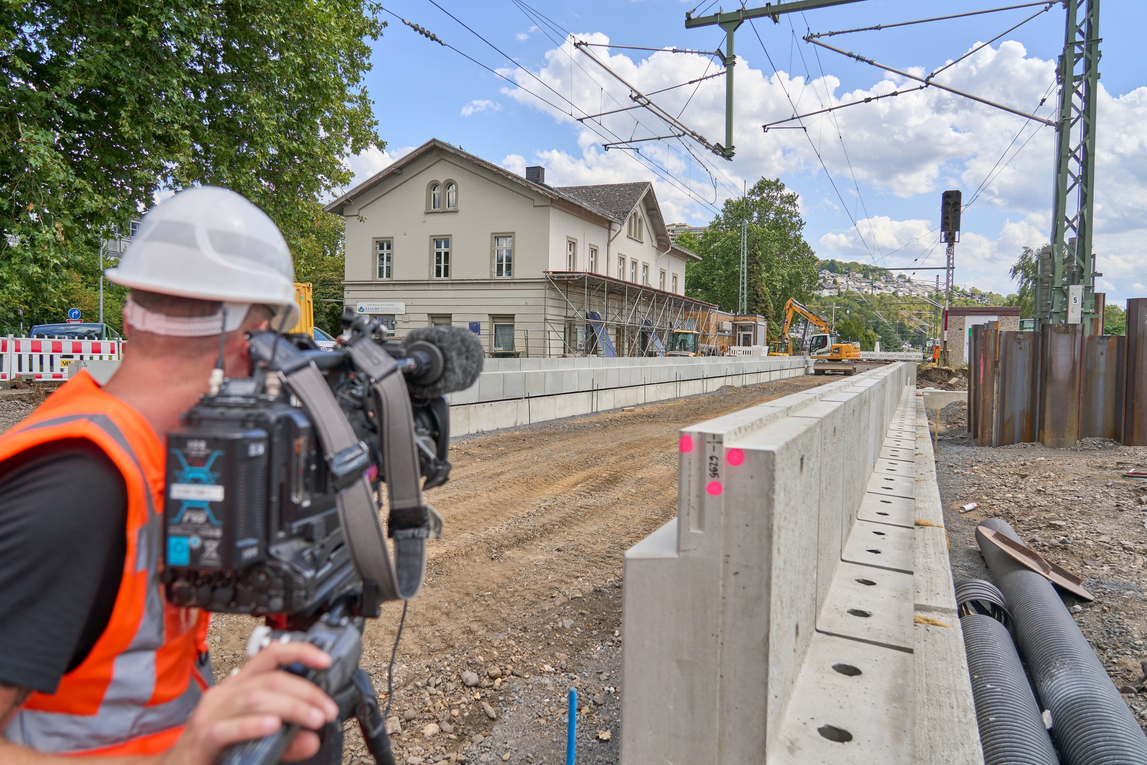 ARCHIV - 05.08.2026, Rheinland-Pfalz, Neuwied: Ein Kameramann macht eine Aufnahme. Die Generalsanierung der Bahnstrecke zwischen Troisdorf und Wiesbaden ist seit wenigen Wochen im vollen Gang. Der neue Bahnsteig am Haltepunkt in Vallendar bei Koblenz ist bereits gut zu erkennen. Ein Kameramann filmt die Arbeiten. (zu dpa: «Bahn saniert linke Rheinstrecke 2028 nur zum Teil») Foto: Sascha Ditscher/dpa +++ dpa-Bildfunk +++