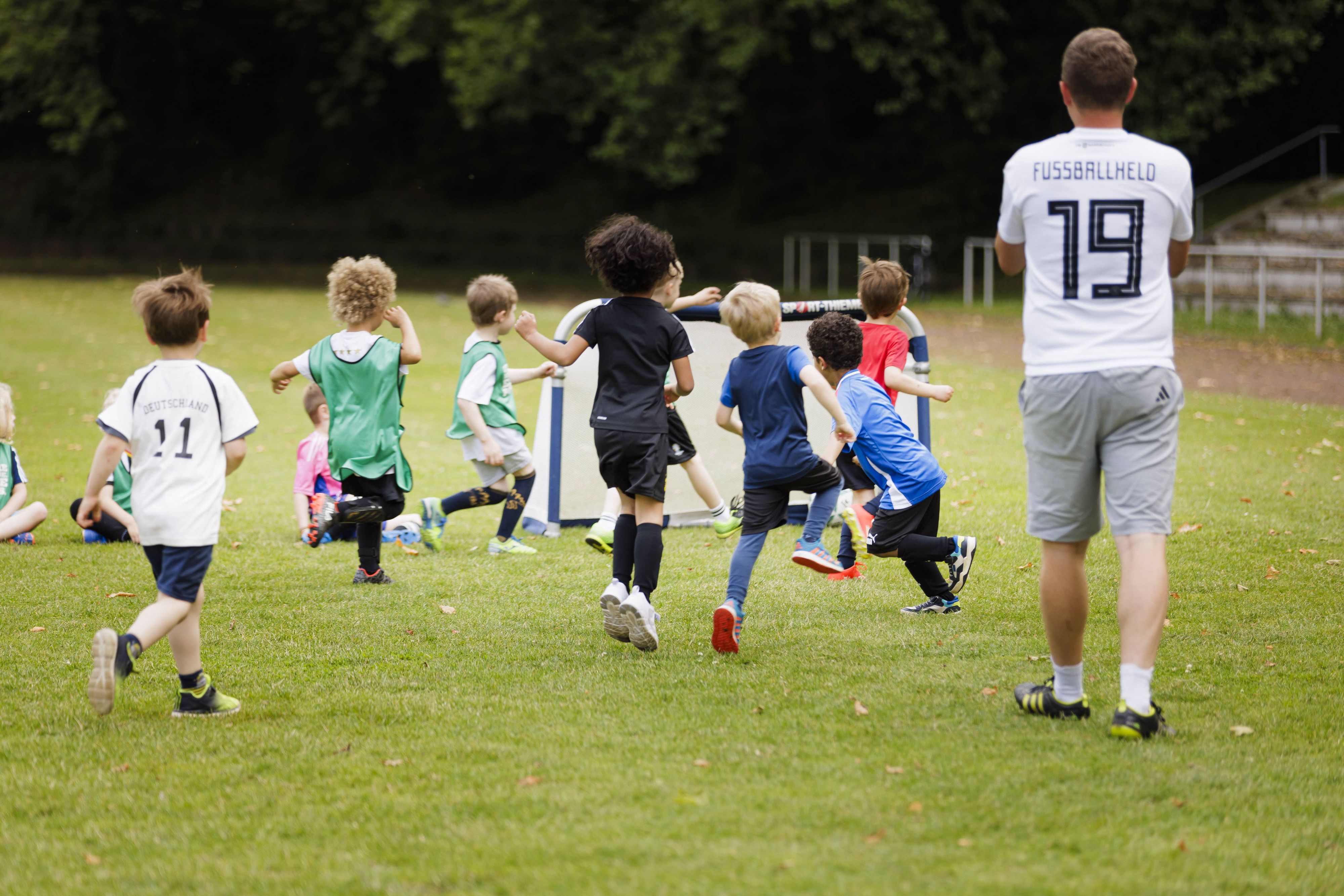 Kinder spielen auf einem Sportplatz Fußball.