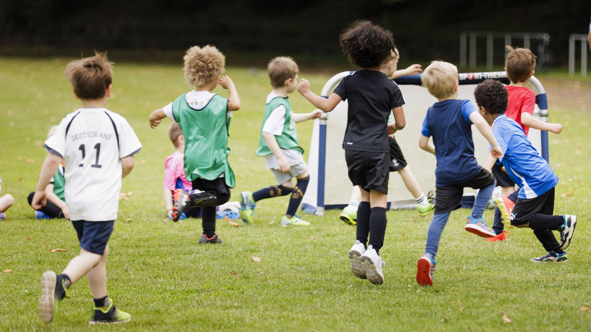 Kinder spielen auf einem Sportplatz Fußball.