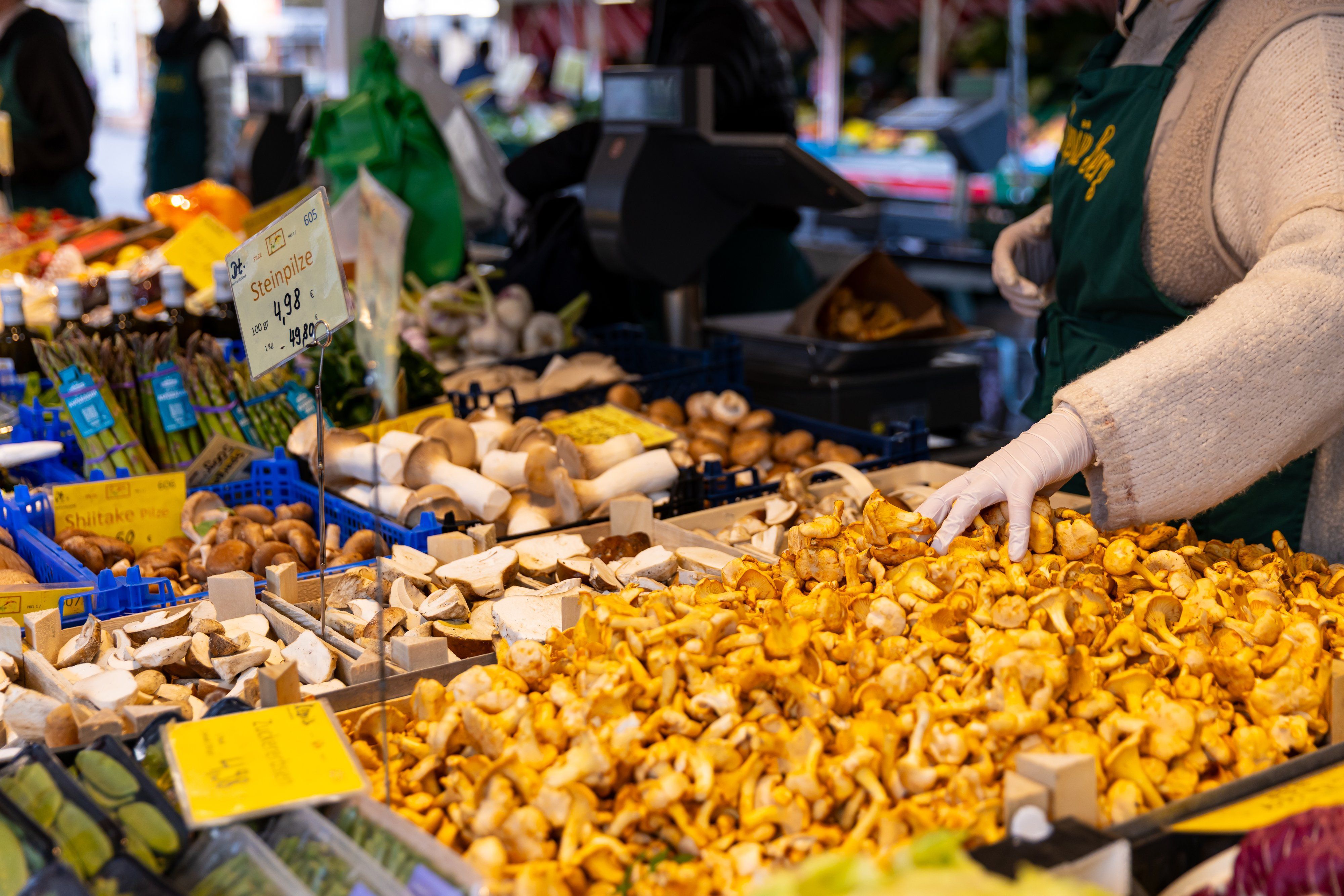 Verkäuferin sortiert Pfifferlinge und Steinpilze am Marktstand