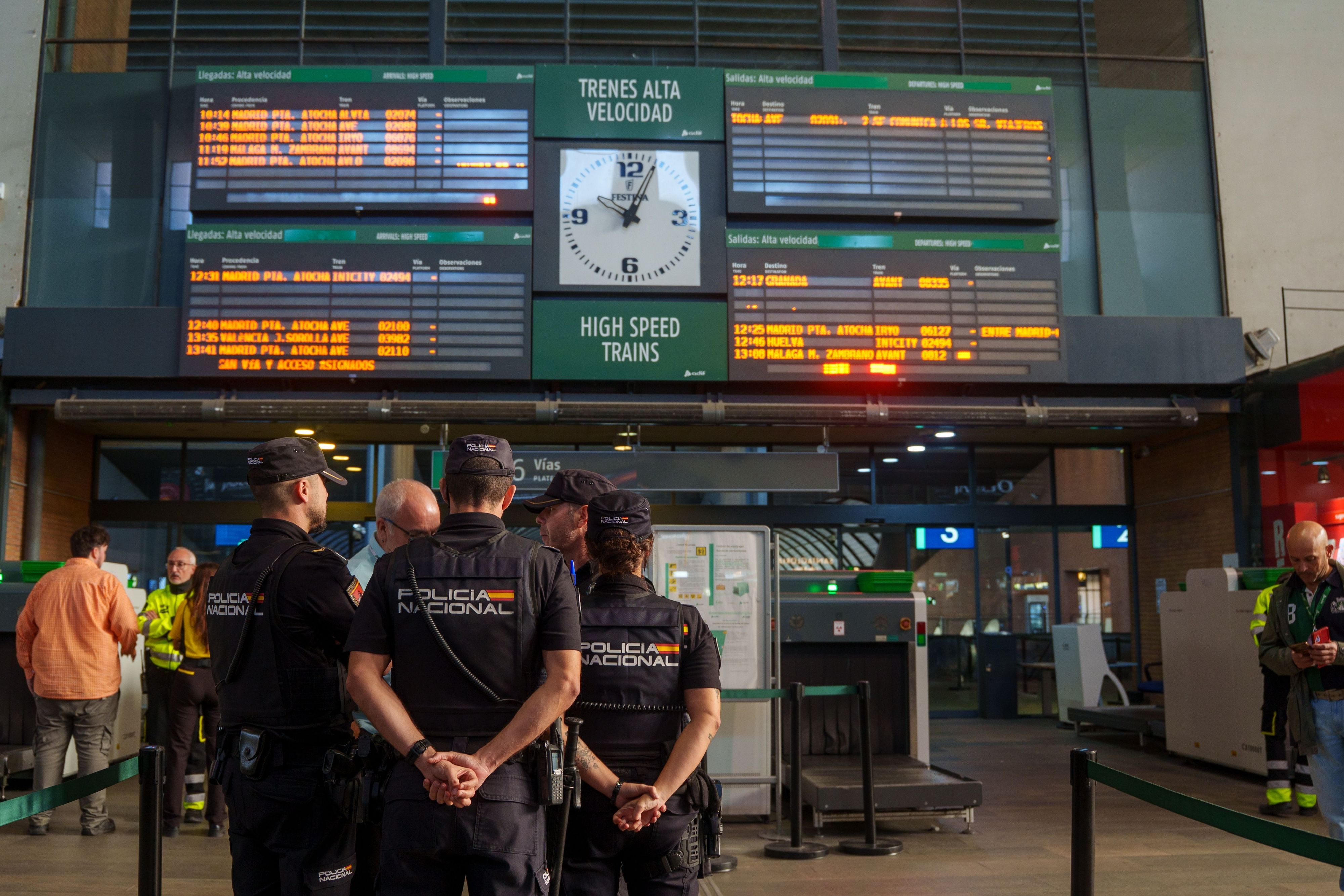 Polizisten stehen vor der Informationsanzeige am Bahnhof Santa Justa, auf dem die Unterbrechung des Zugverkehrs zwischen Madrid und Andalusien nach dem Zugunglück angezeigt wird.