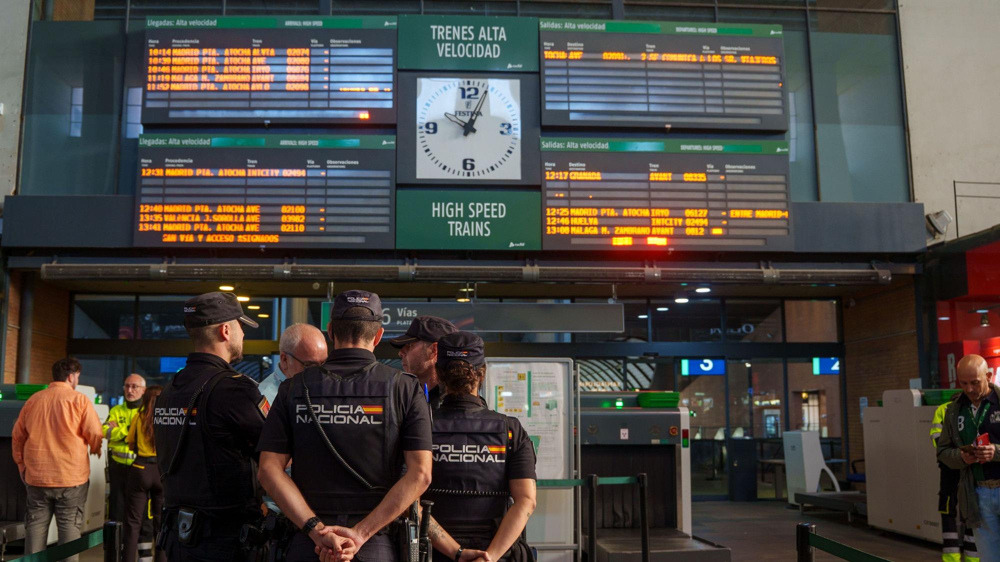 Polizisten stehen vor der Informationsanzeige am Bahnhof Santa Justa, auf dem die Unterbrechung des Zugverkehrs zwischen Madrid und Andalusien nach dem Zugunglück angezeigt wird.