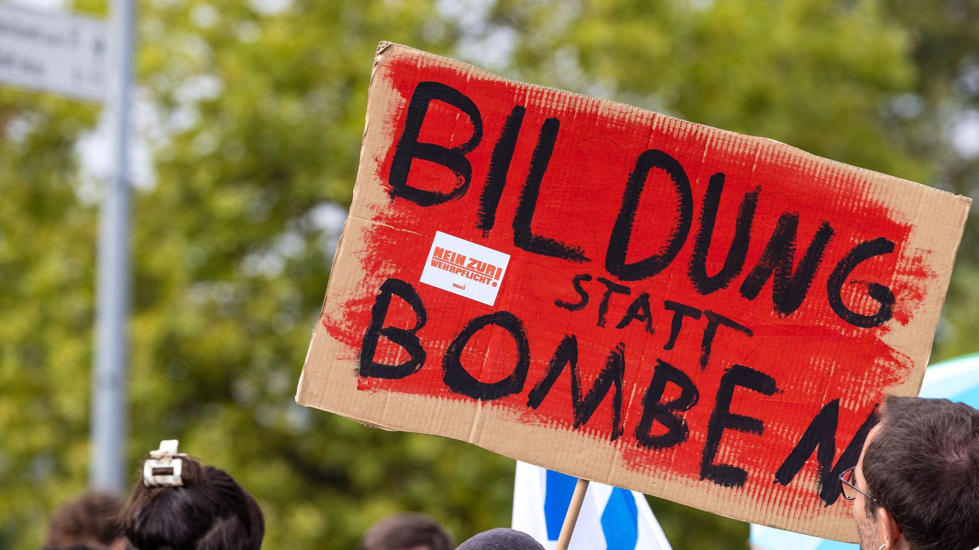 „Bildung statt Bomben“ steht auf dem Plakat eines Teilnehmers einer Demonstration. Gegen Wehrpflicht und Sozialkürzungen richtet sich auch „Gen Z regelt“. (Symbolbild)