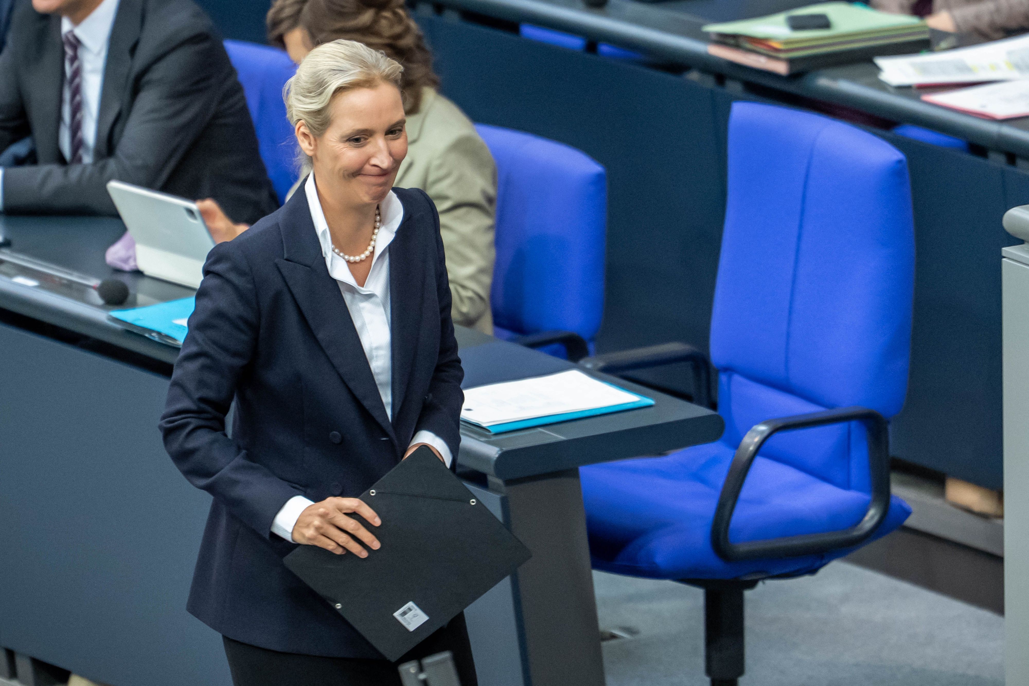 Alice Weidel, Bundesvorsitzende und Fraktionsvorsitzende der AfD, geht vor dem leeren Stuhl von Bundeskanzler Merz im Plenarsaal im Bundestag.