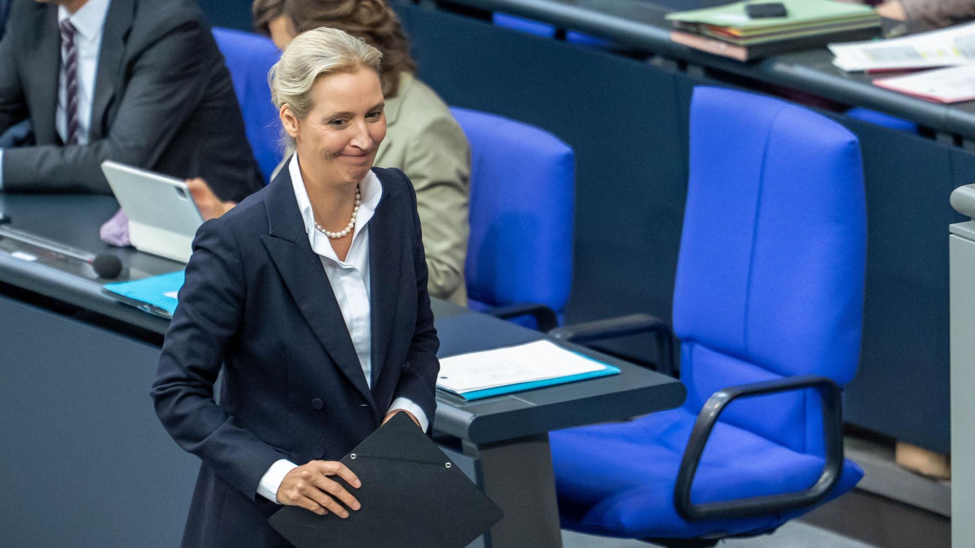 Alice Weidel, Bundesvorsitzende und Fraktionsvorsitzende der AfD, geht vor dem leeren Stuhl von Bundeskanzler Merz im Plenarsaal im Bundestag.