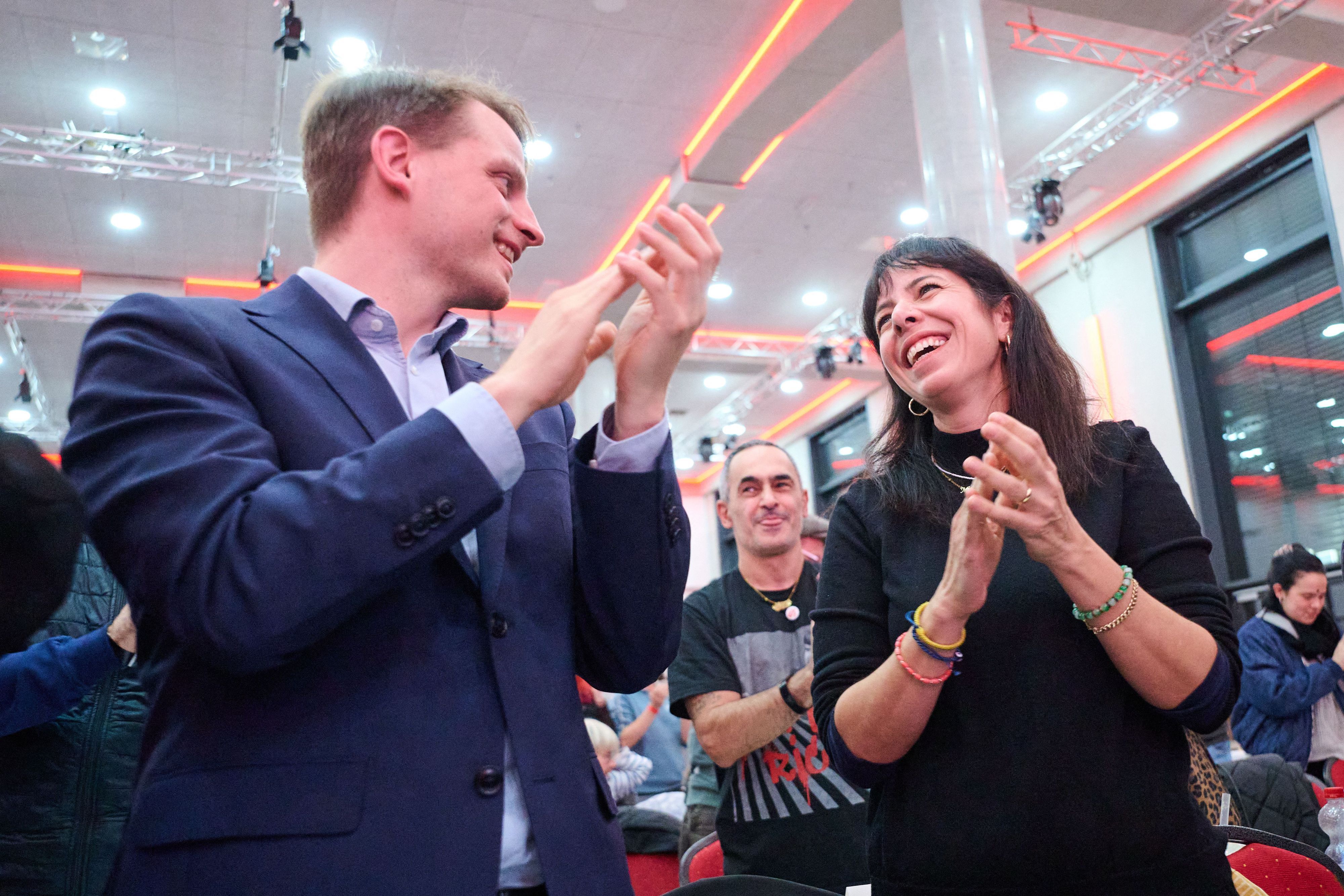 31.10.2026, Berlin: Elif Eralp (r), stellvertretende Vorsitzende der Partei Die Linke in Berlin, und Maximilian Schirmer, Vorsitzender der Partei Die Linke in Berlin, jubeln während des Landesparteitags der Partei Die Linke Berlin nach der Zustimmung zu Koalitionsgesprächen. Sechs Wochen nach der Wahl zum Berliner Abgeordnetenhaus entscheidet die Berliner Linke über den Start von Koalitionsverhandlungen mit Grünen und SPD. Foto: Sebastian Christoph Gollnow/dpa +++ dpa-Bildfunk +++
