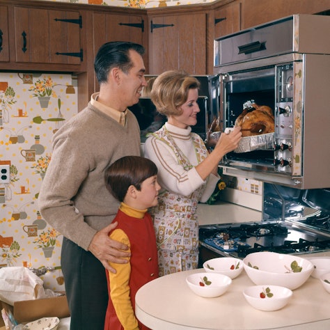 In den 60er Jahren holt eine Hausfrau einen Braten aus dem Ofen.