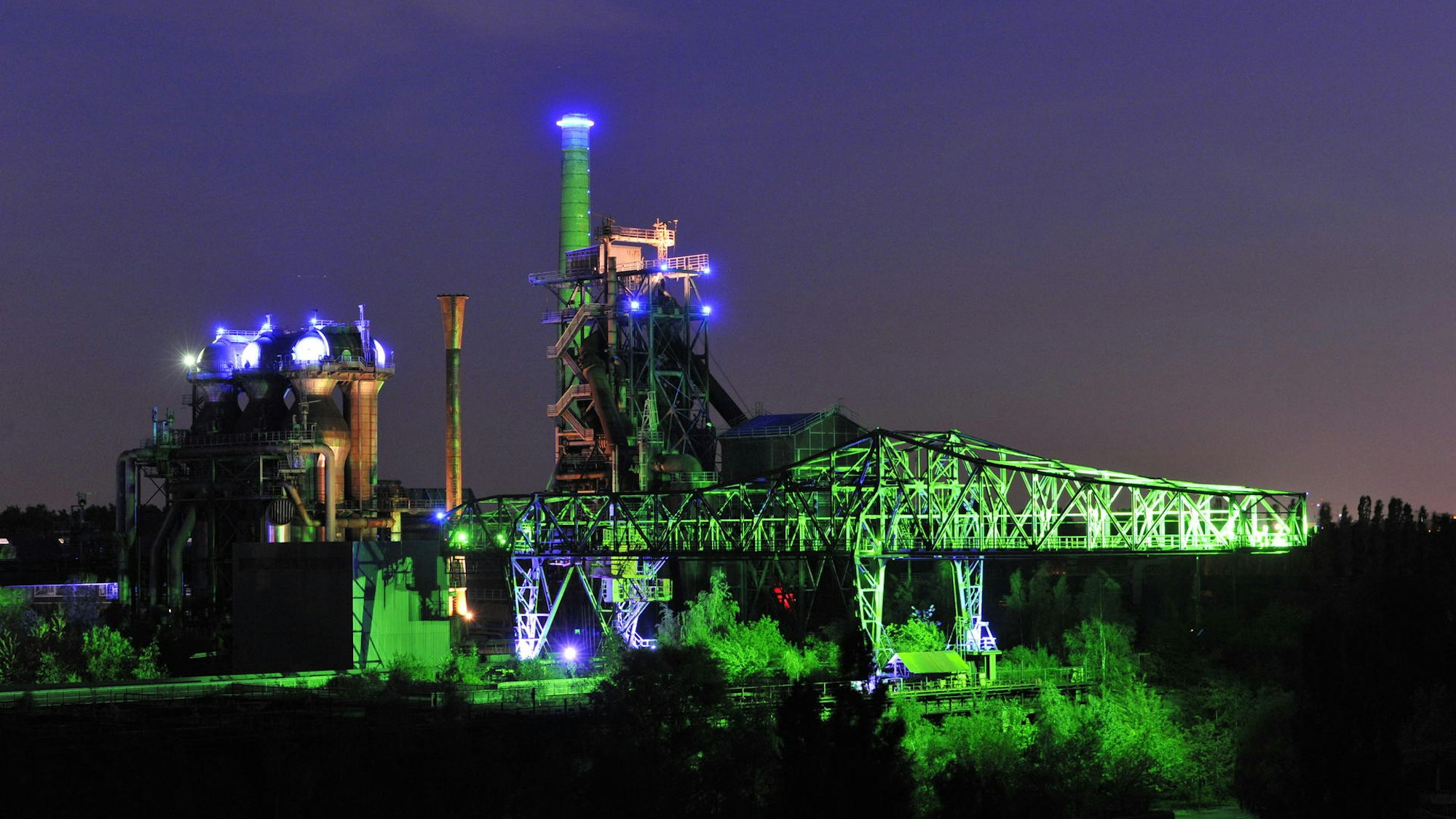 Die Industriebauten werden in grün angestrahlt.