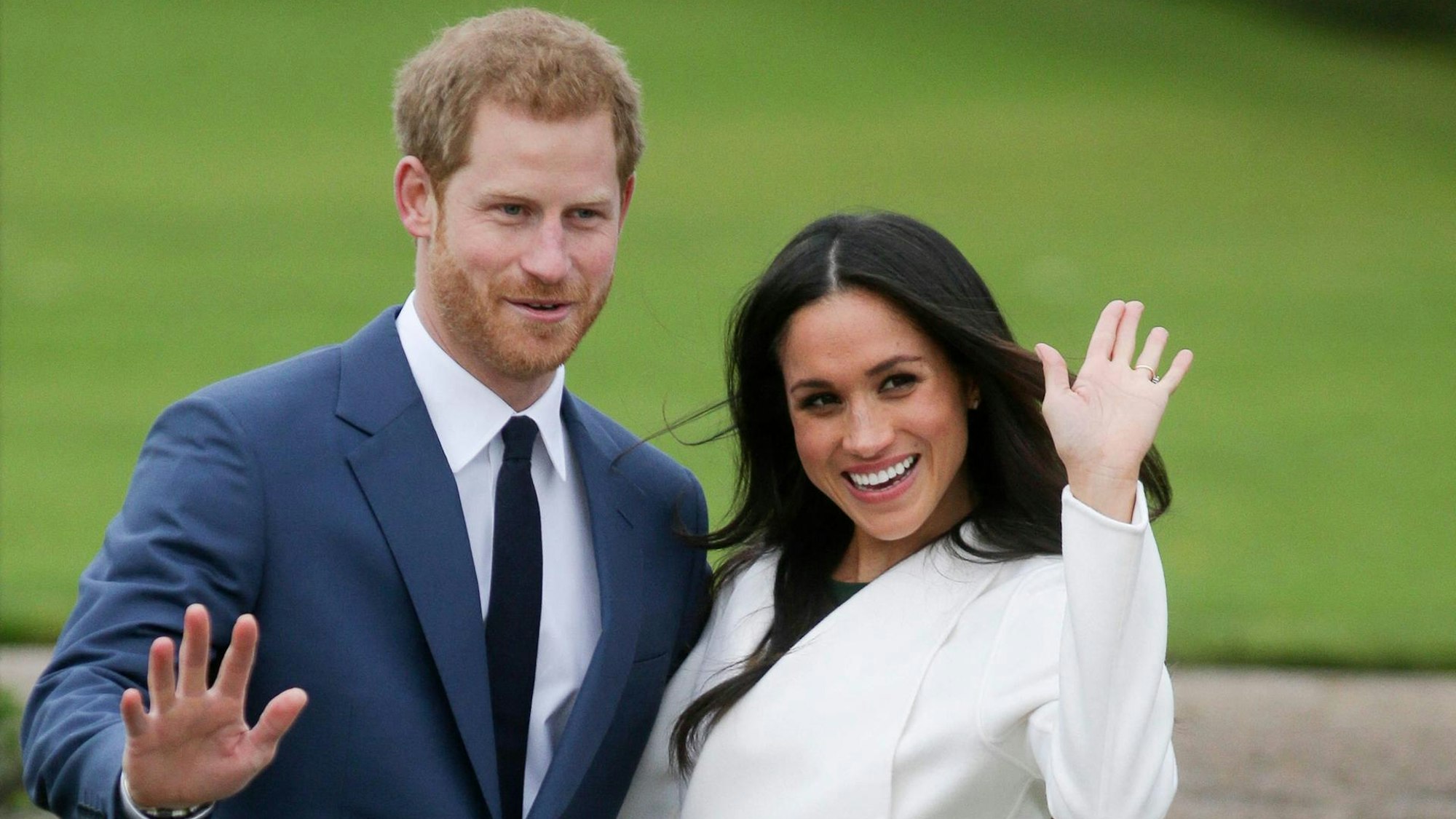 Prinz Harry und Herzogin Meghan winken freudig.