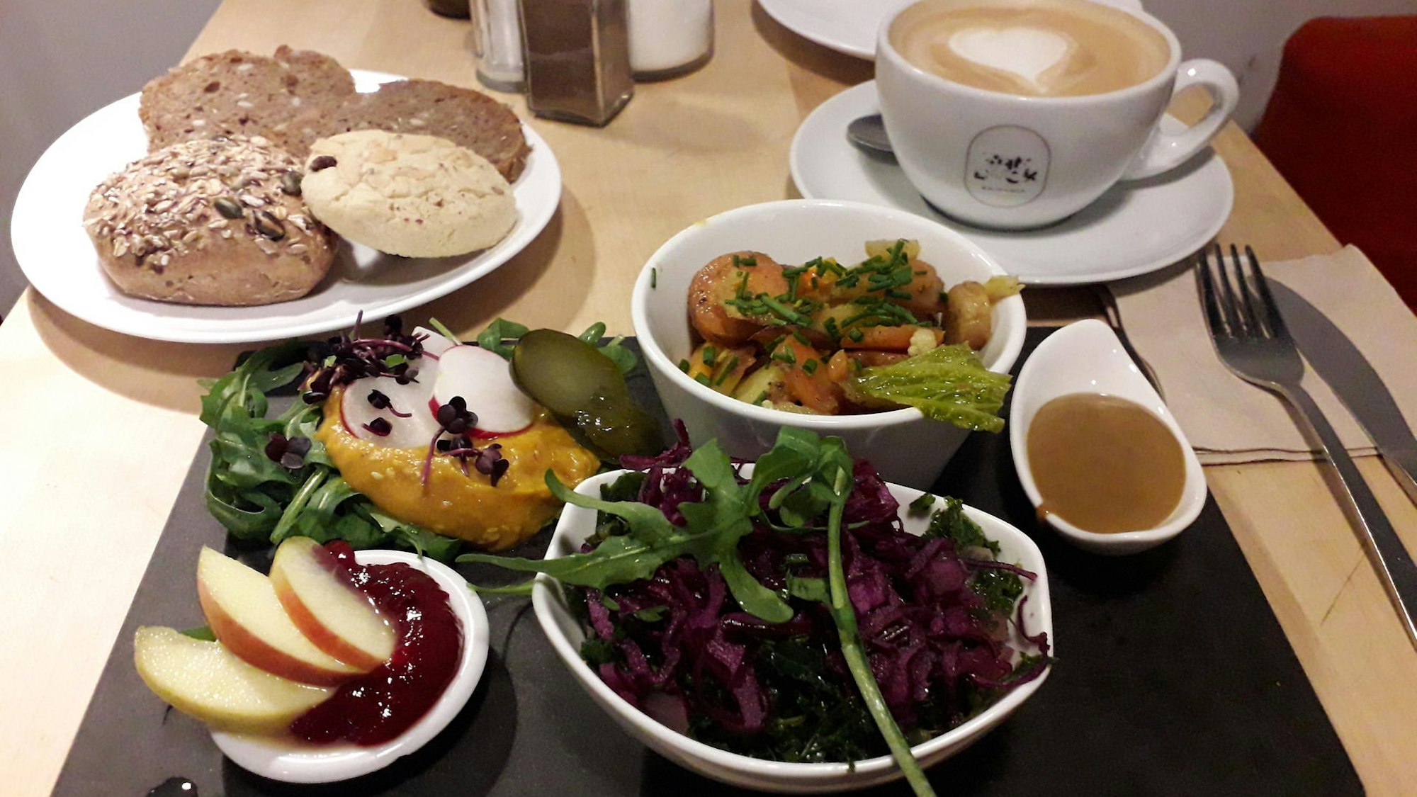 Ein veganes Frühstücksbrettchen mit Salaten, Brot und mehr