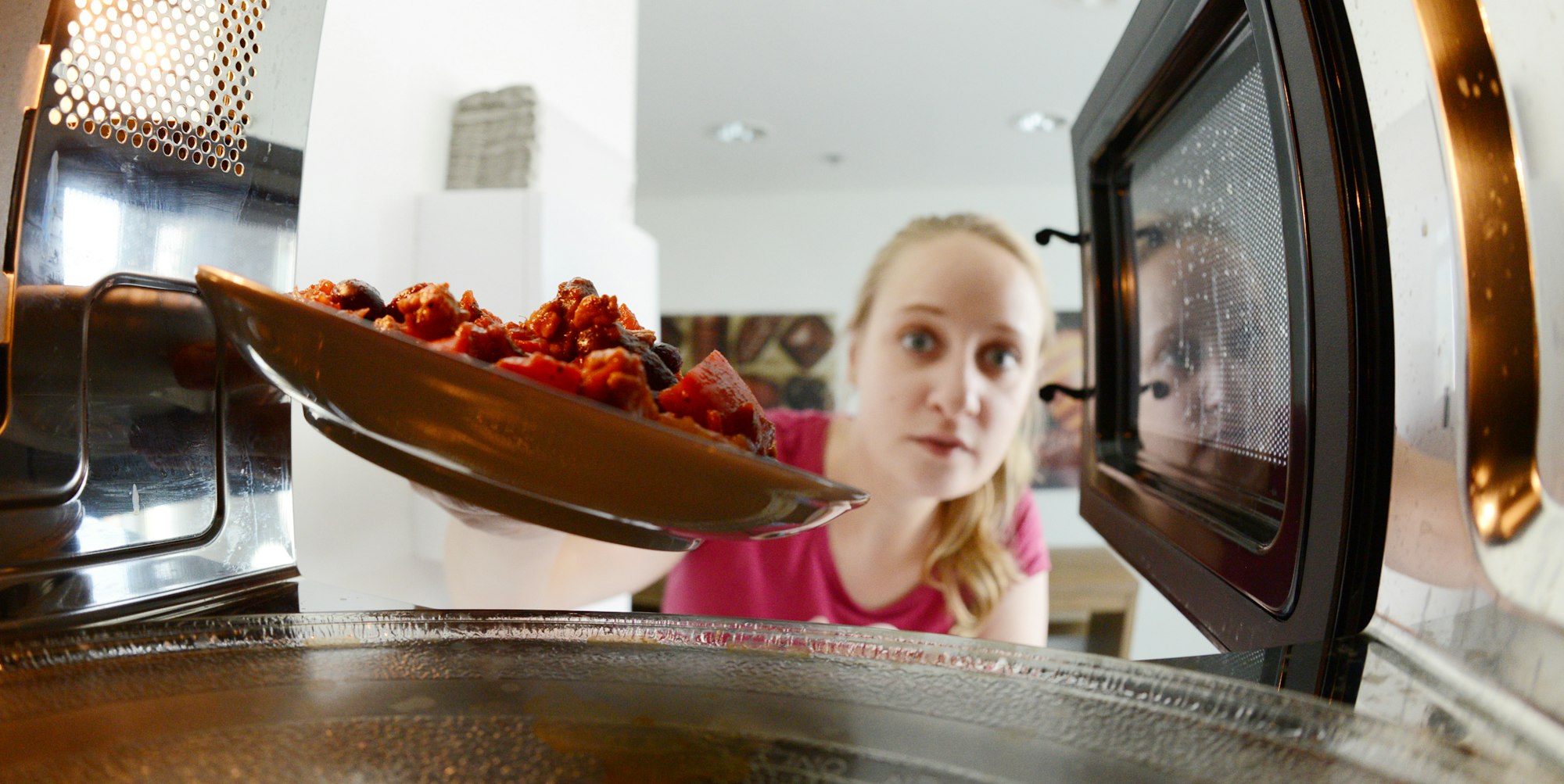 Frau stellt Essen in Mikrowelle