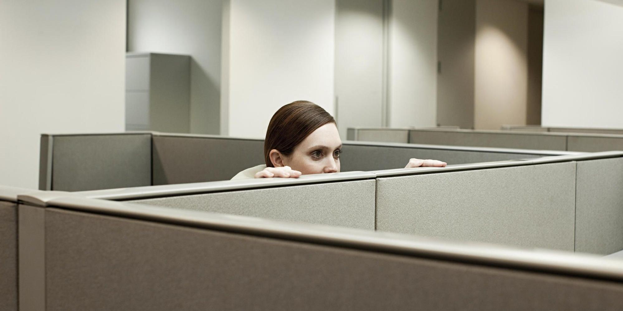 Eine Frau schaut in einem Büro über eine Trennwand.