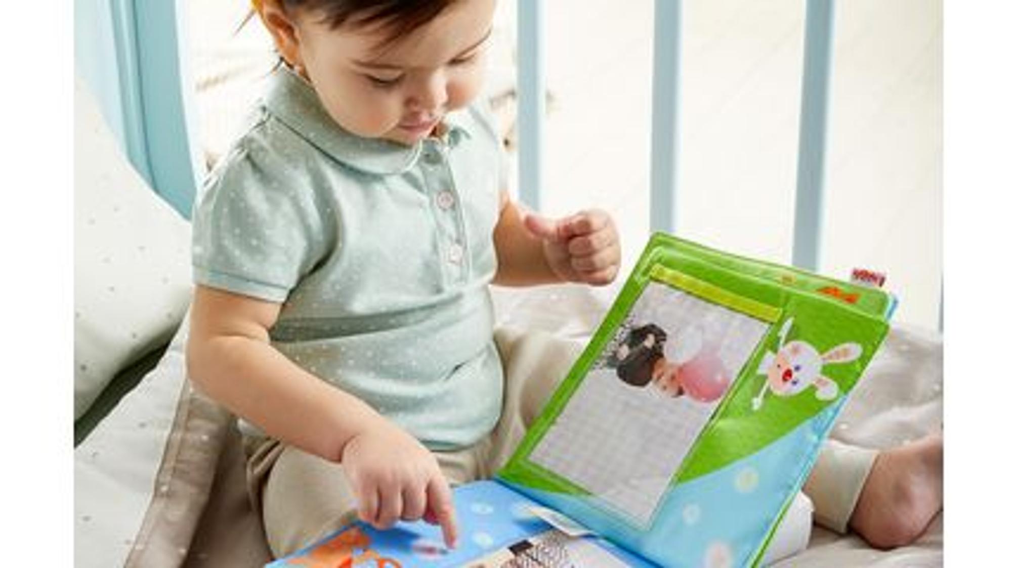 Ein Baby guckt ein Fotobuch an.