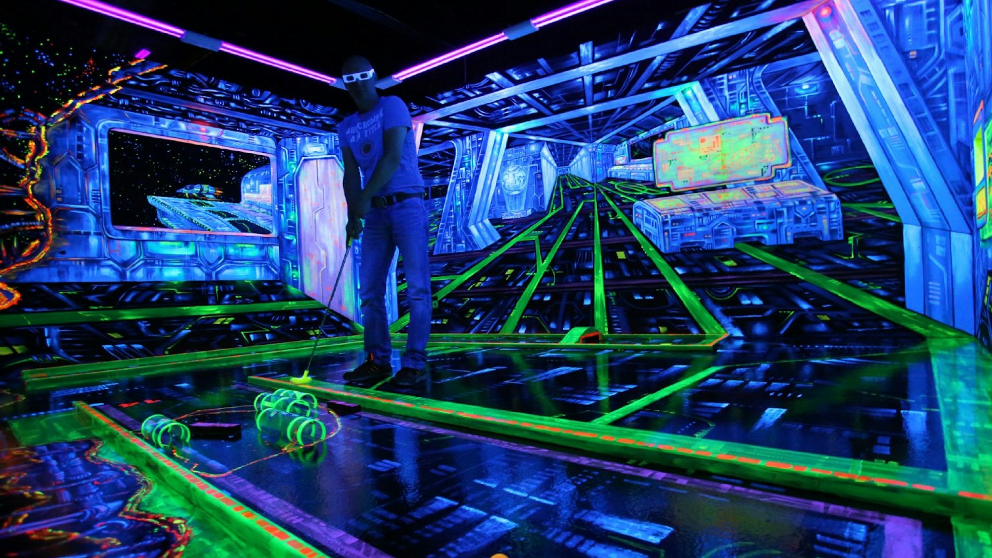 Ein Mensch spielt Schwarzlichtminigolf