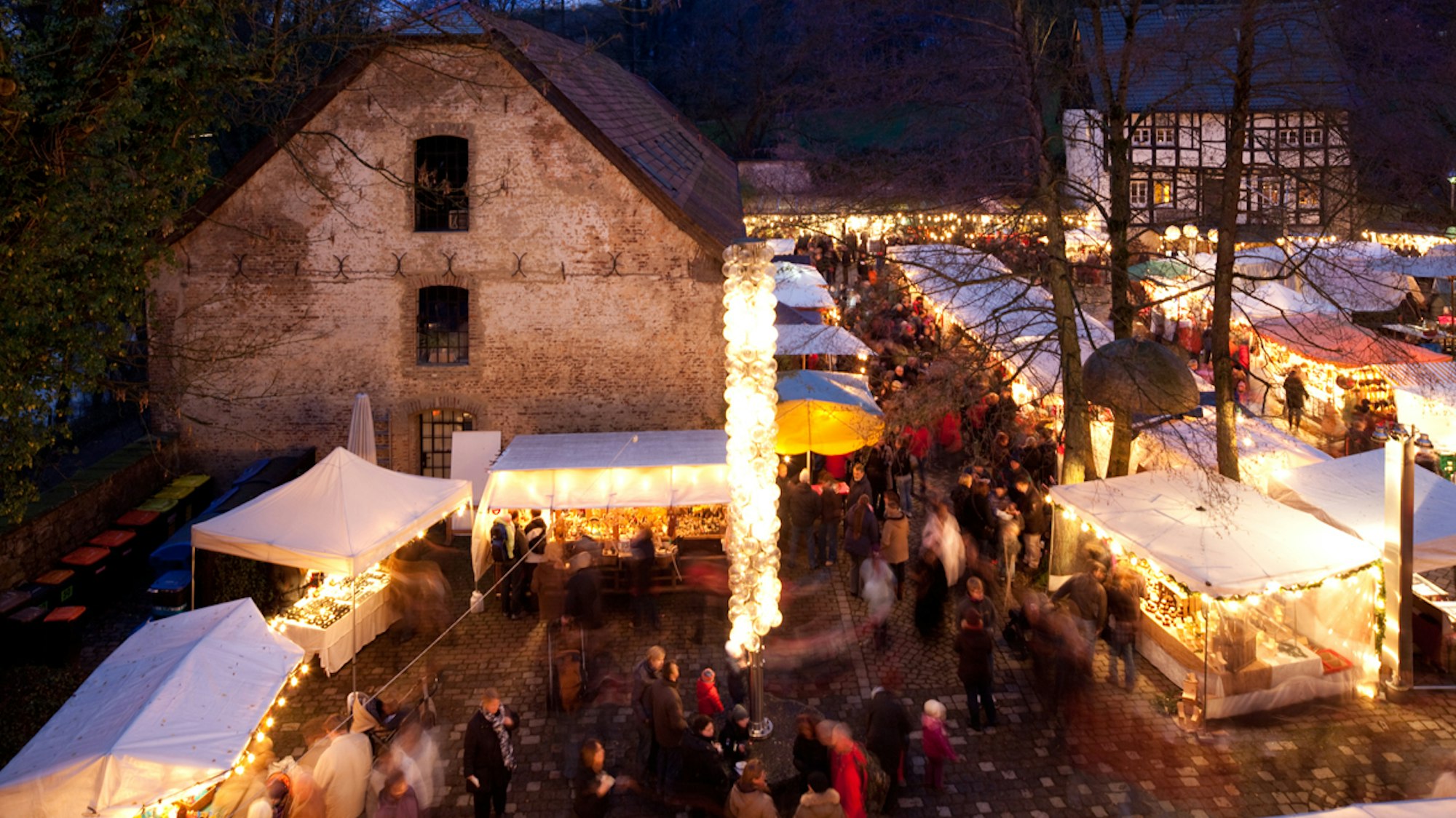 Weihnachtsmarktstände und bunte Lichter vor Burganlage in Wuppertal.