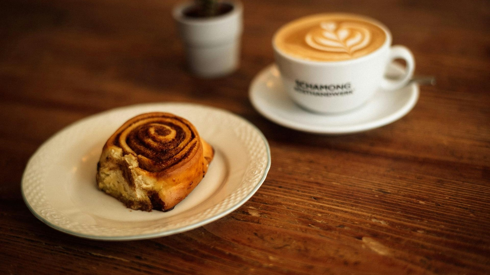 Eine Zimtschnecke steht auf einem Teller auf einem Tisch