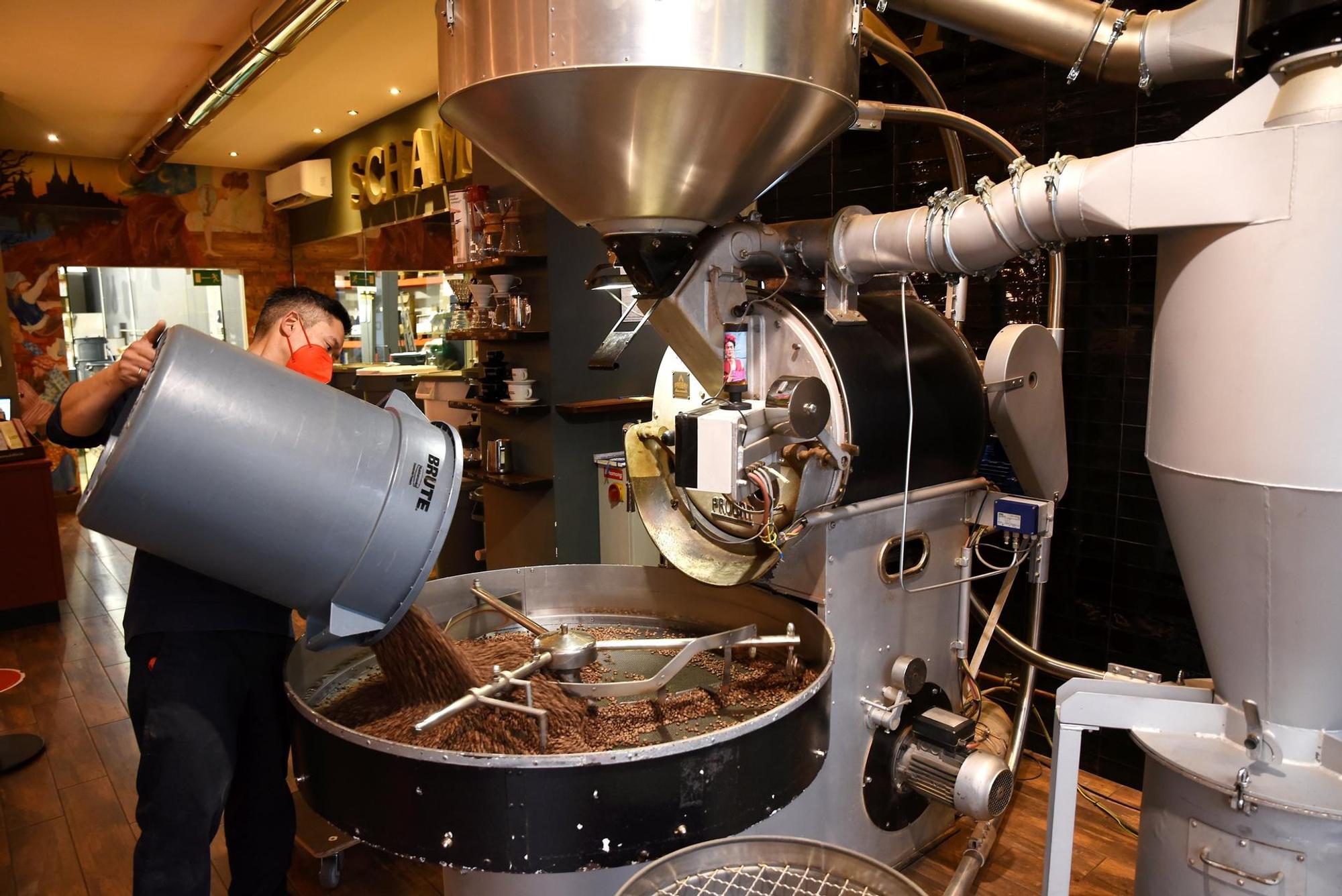 Ein Mann schüttet Kaffeebohnen in eine große Maschine zum Rösten.