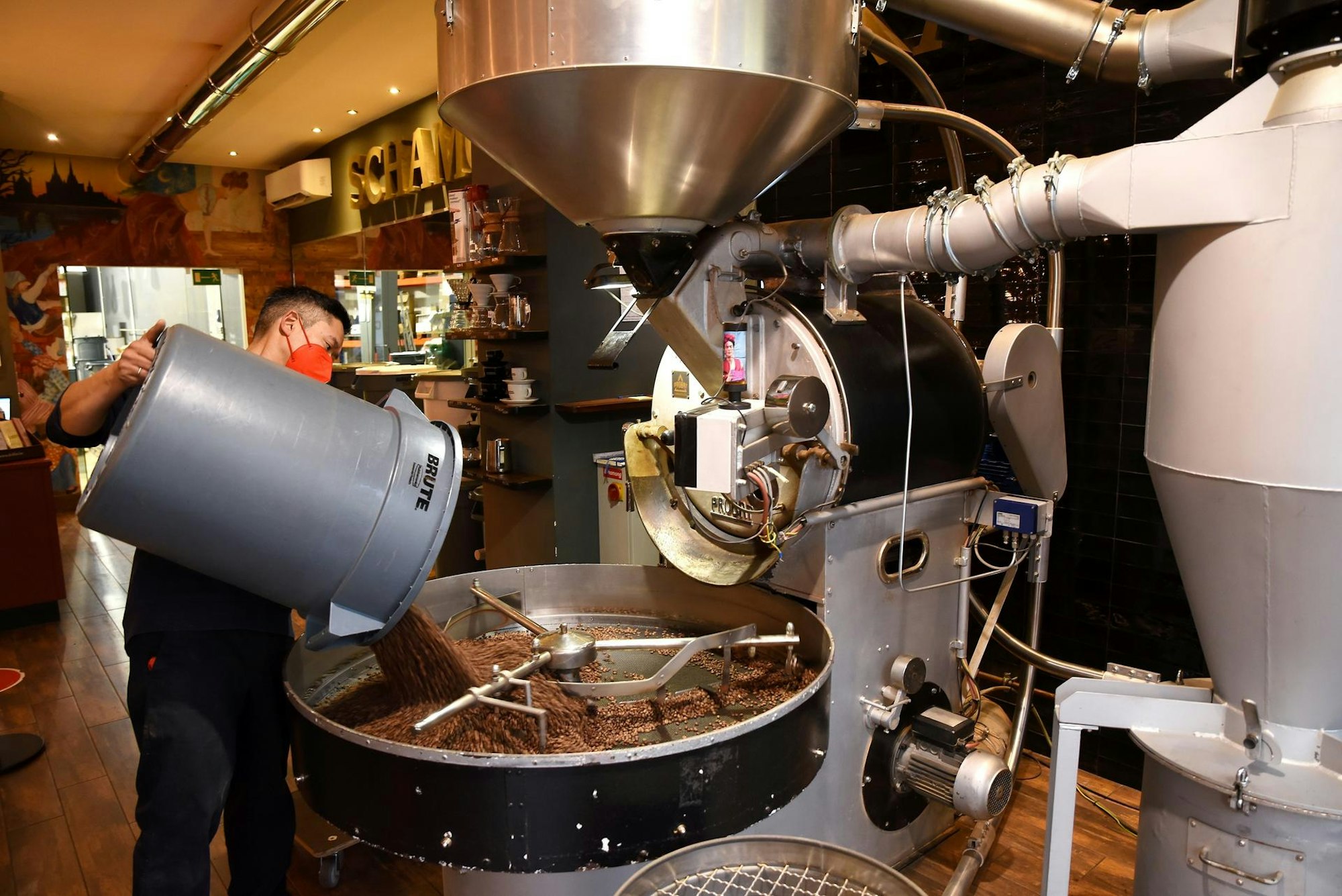 Ein Mann schüttet Kaffeebohnen in eine große Maschine zum Rösten.