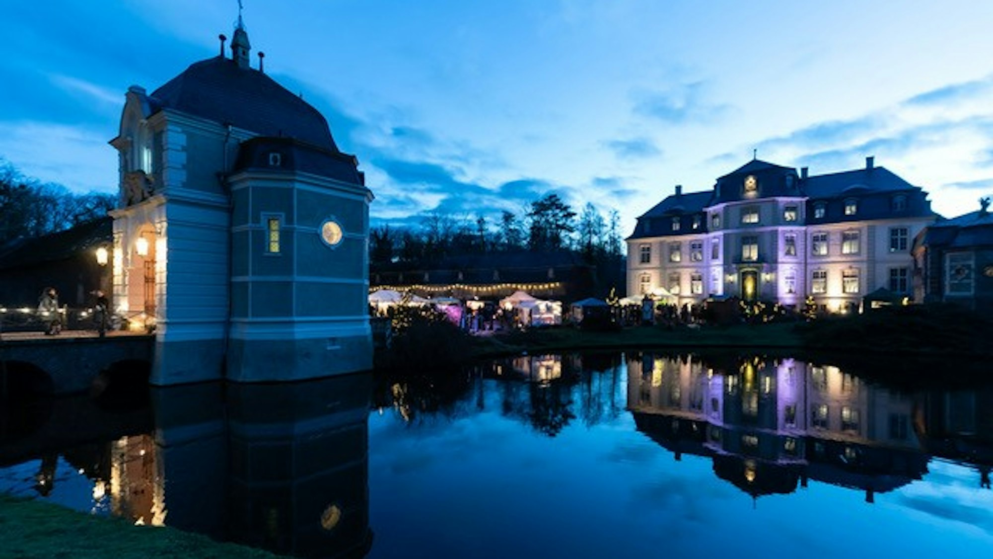Schloss Türnich im Abendlicht mit See im Vordergrund.