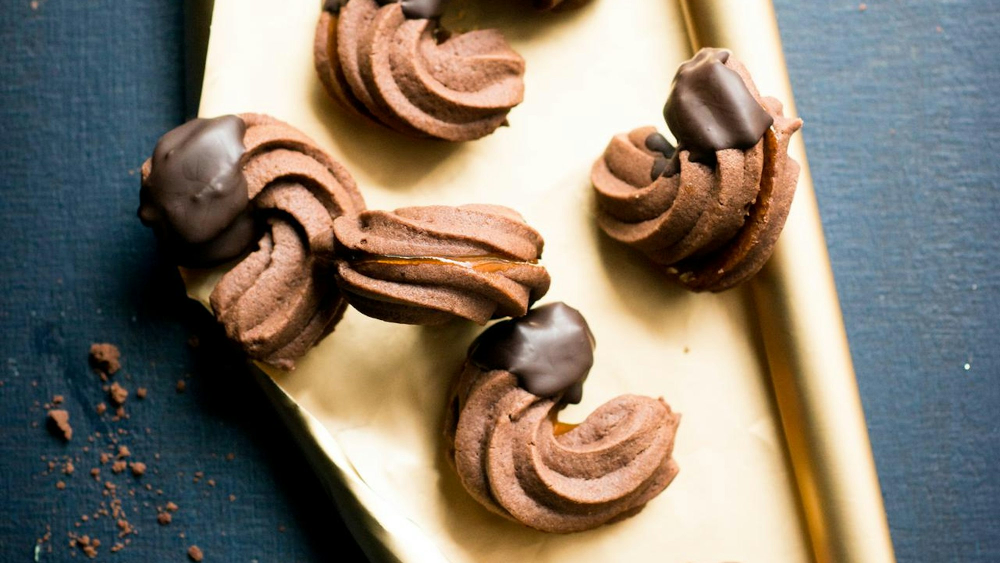 Schokoladen-Sicheln liegen auf einem goldenen Backpapier lecker angerichtet mit eingetauchten Schoko-Enden.