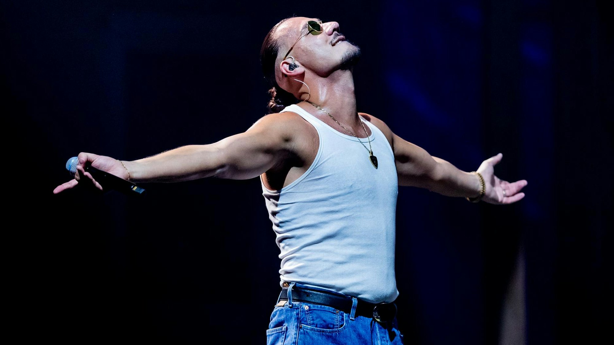 Apache 207 auf der Bühne. Er streckt die Arme aus.