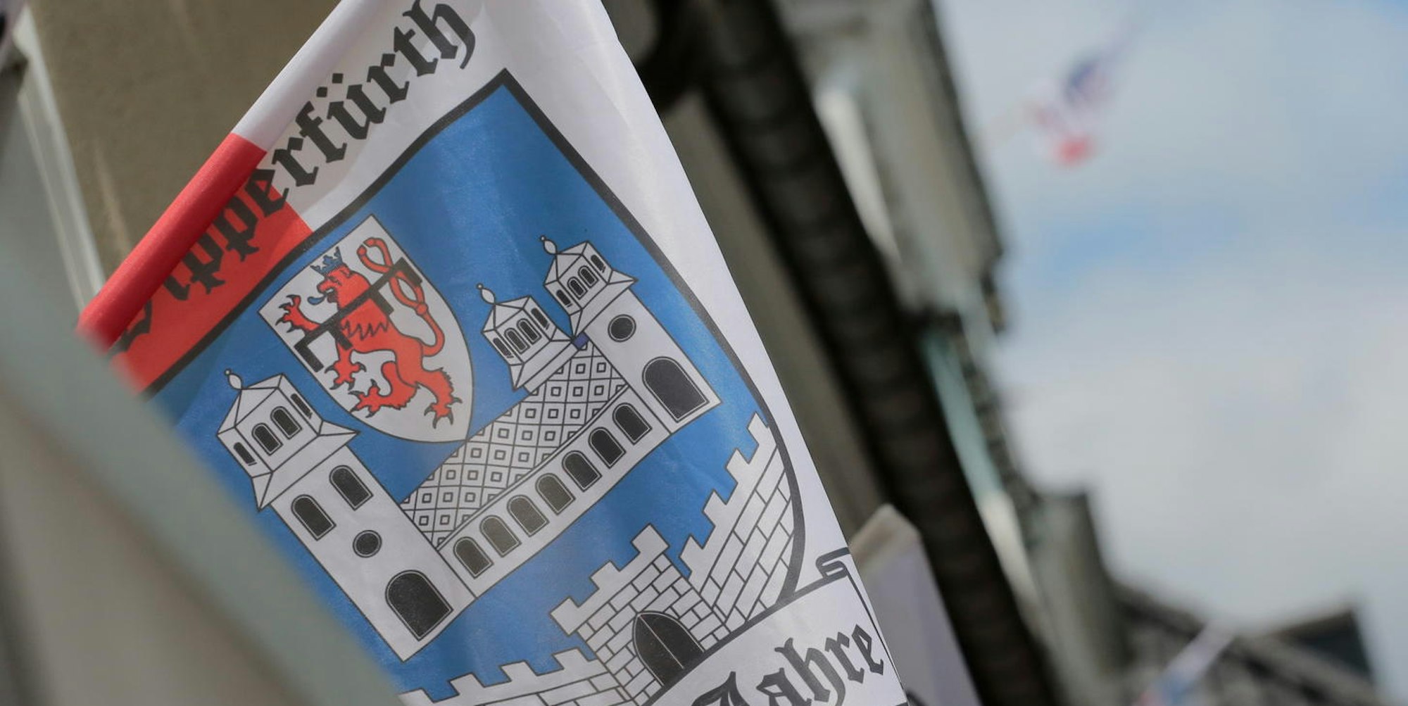 Die Stadtfahne von Wipperfürth weht aus dem Fenster eines Gebäudes.