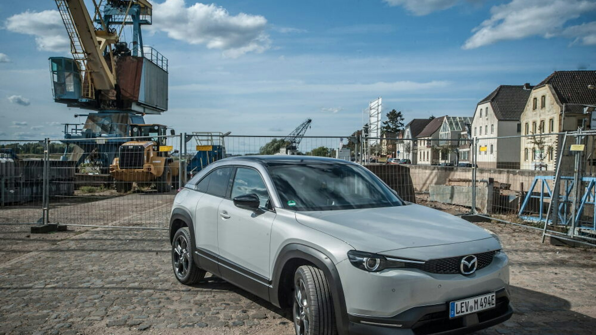 Ein Mazda MX-30 steht vor dem alten Kran im Hitdorfer Hafen.