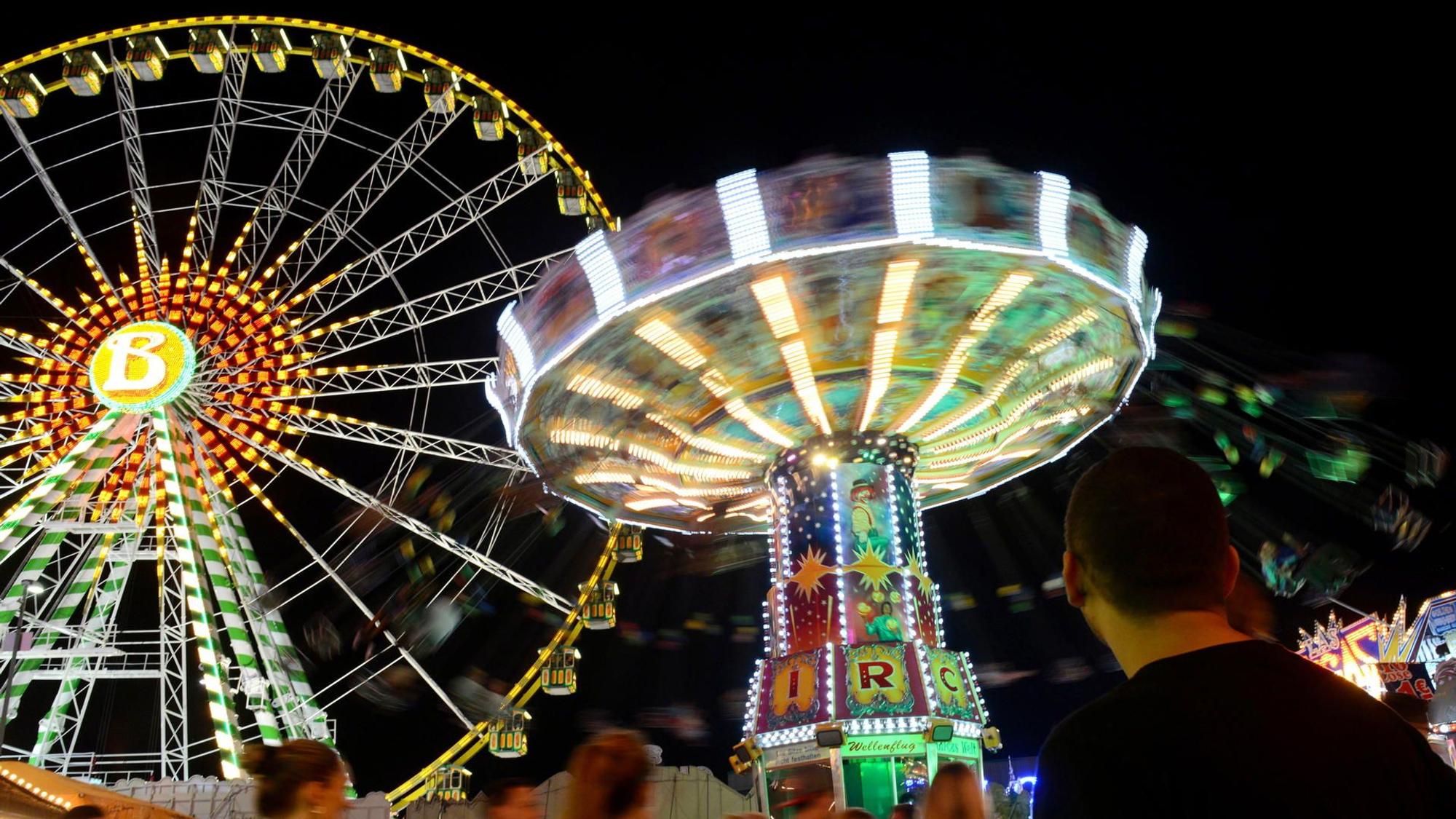 beleuchtetes Riesenrad und Kettenkarussell im Dunkeln