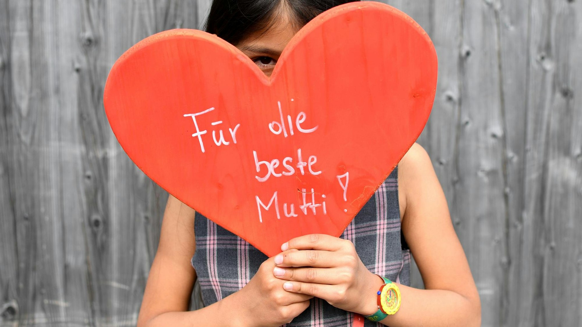 Ein Kind hält ein Schild, auf dem steht "Für die beste Mutti".