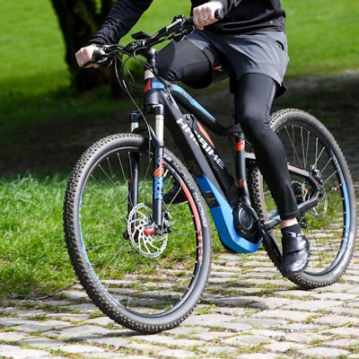 Ein Mann fährt mit einem Pedelec über Kopfsteinpflaster.