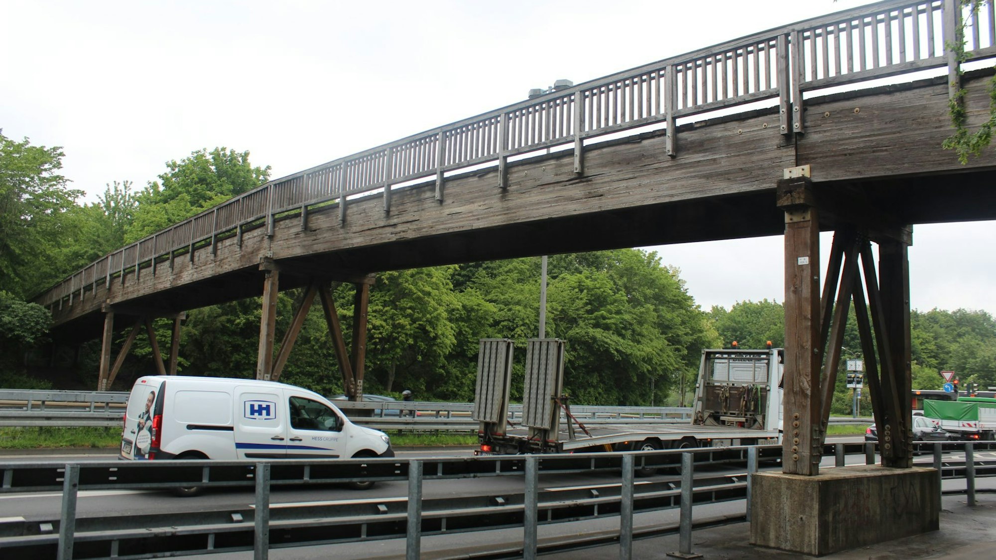 Eine Holzbrücke führt über eine mehrspurige Straße.