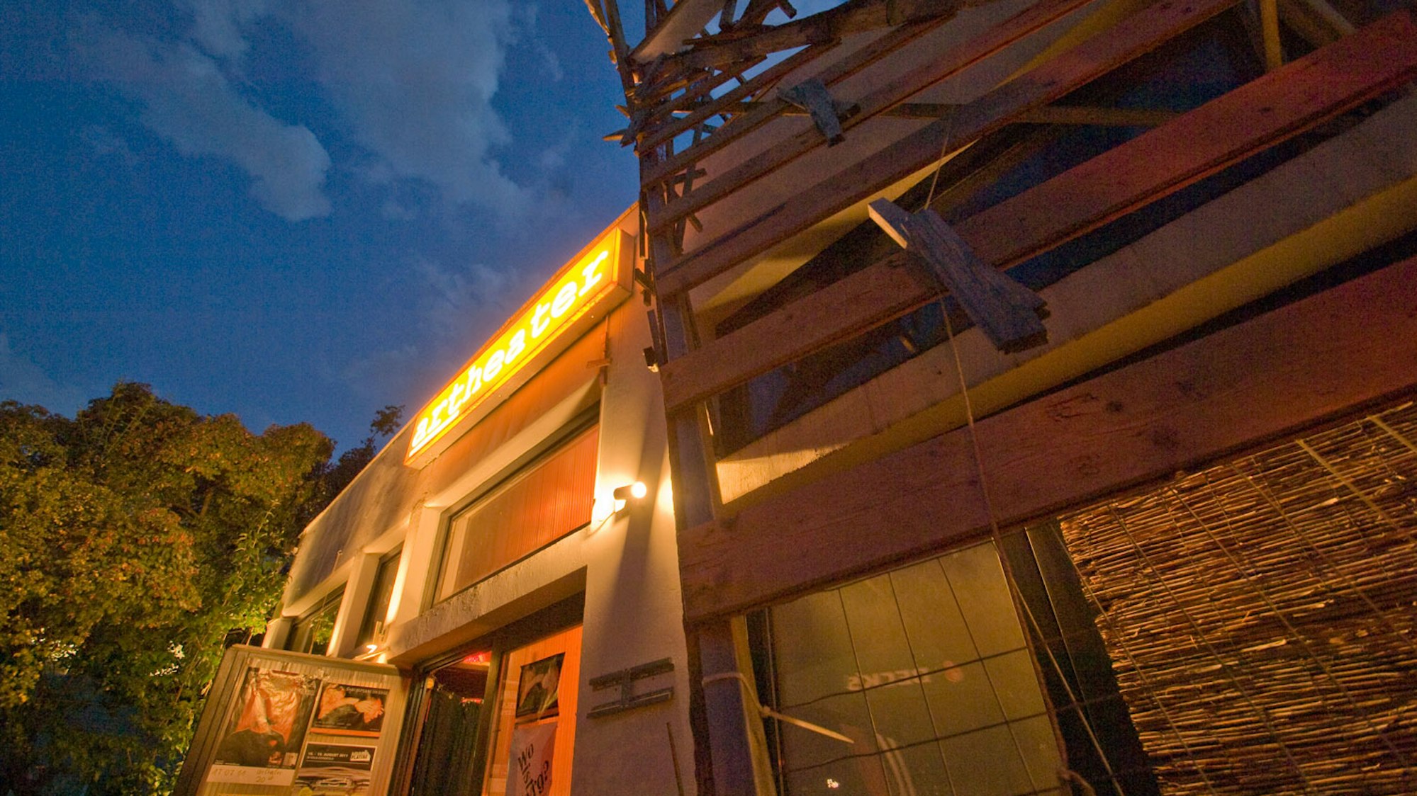 Der teilweise mit Holz verkleidete Außenbereich des Artheater ist in der Dämmerung zu sehen.