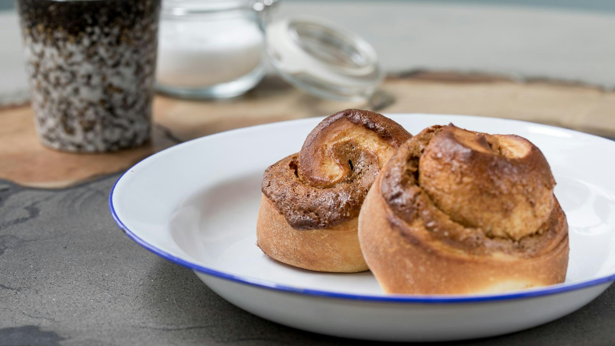 Zwei Zimtschnecken liegen auf einem Teller angerichtet.