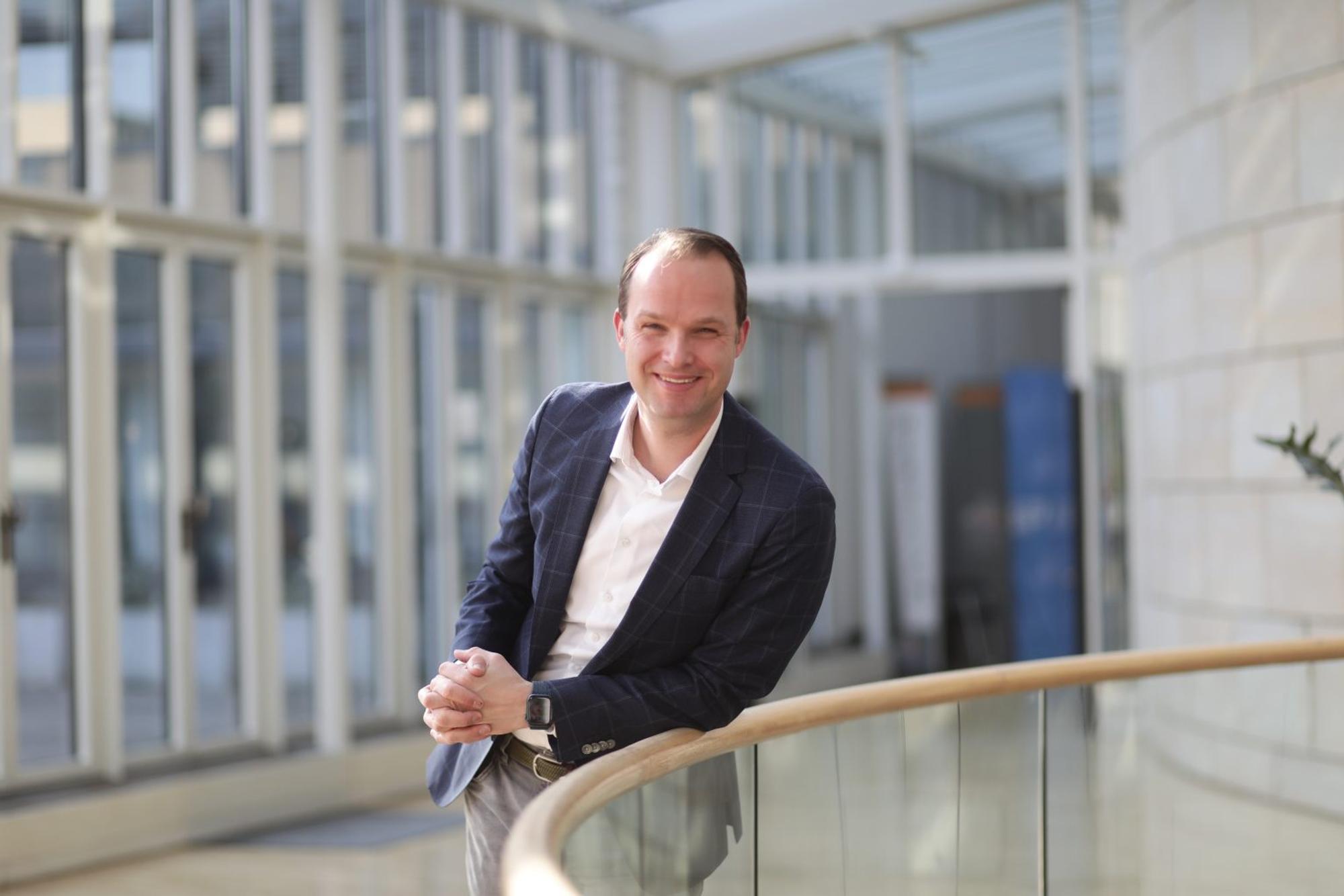Marcel Hafke (FDP) steht im Büro in einem karierten Blazer und einem weißen Hemd
