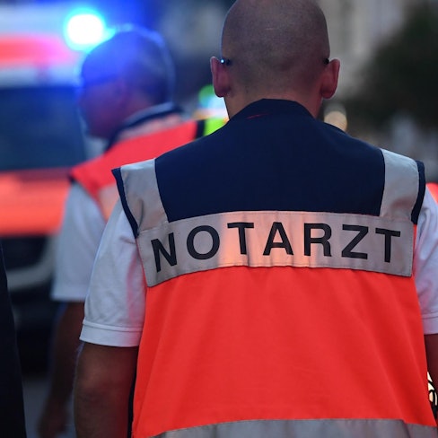 Ein Notarzt mit einer Weste steht an einem Unfallort.